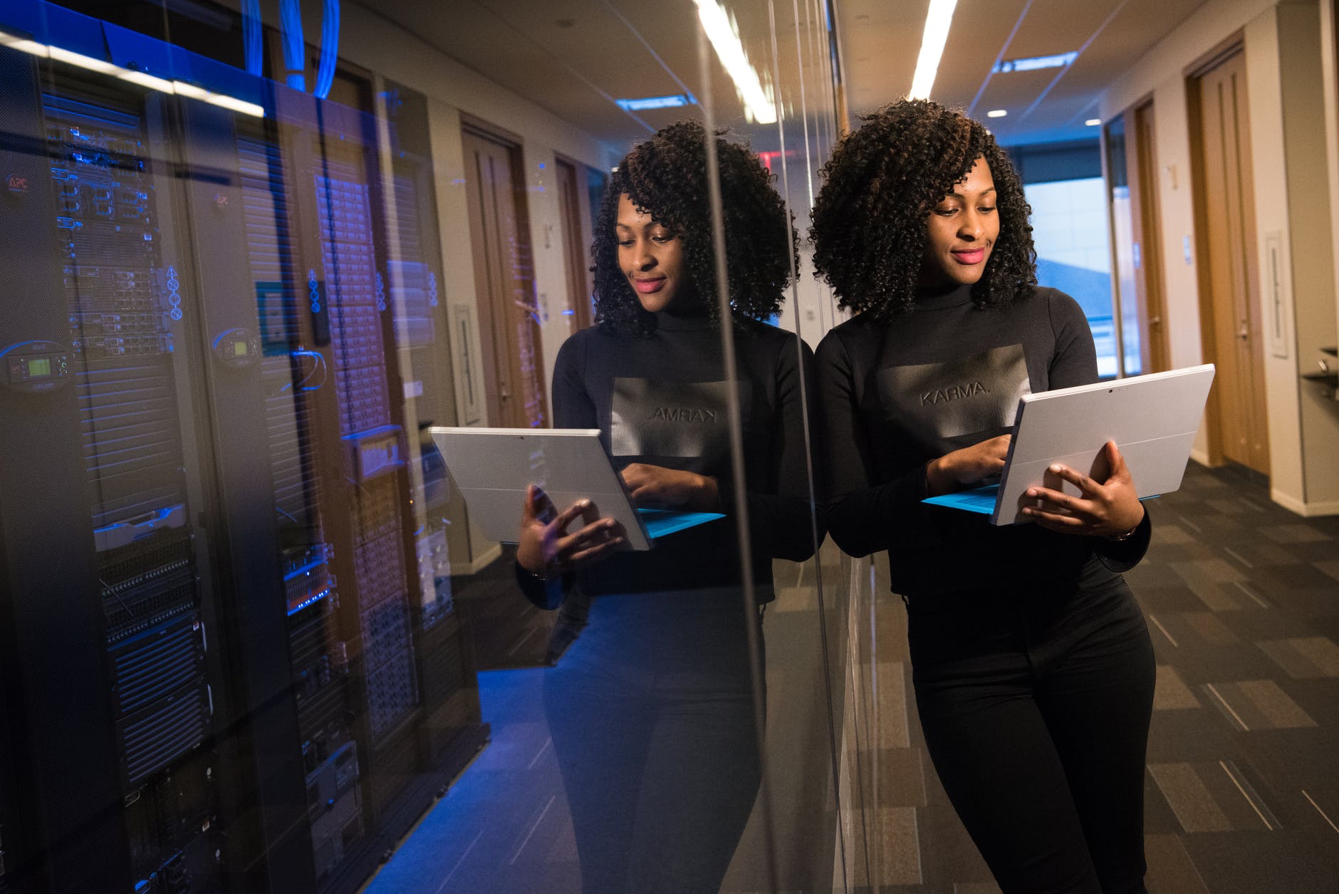 Black woman using laptop while leaning on mirror