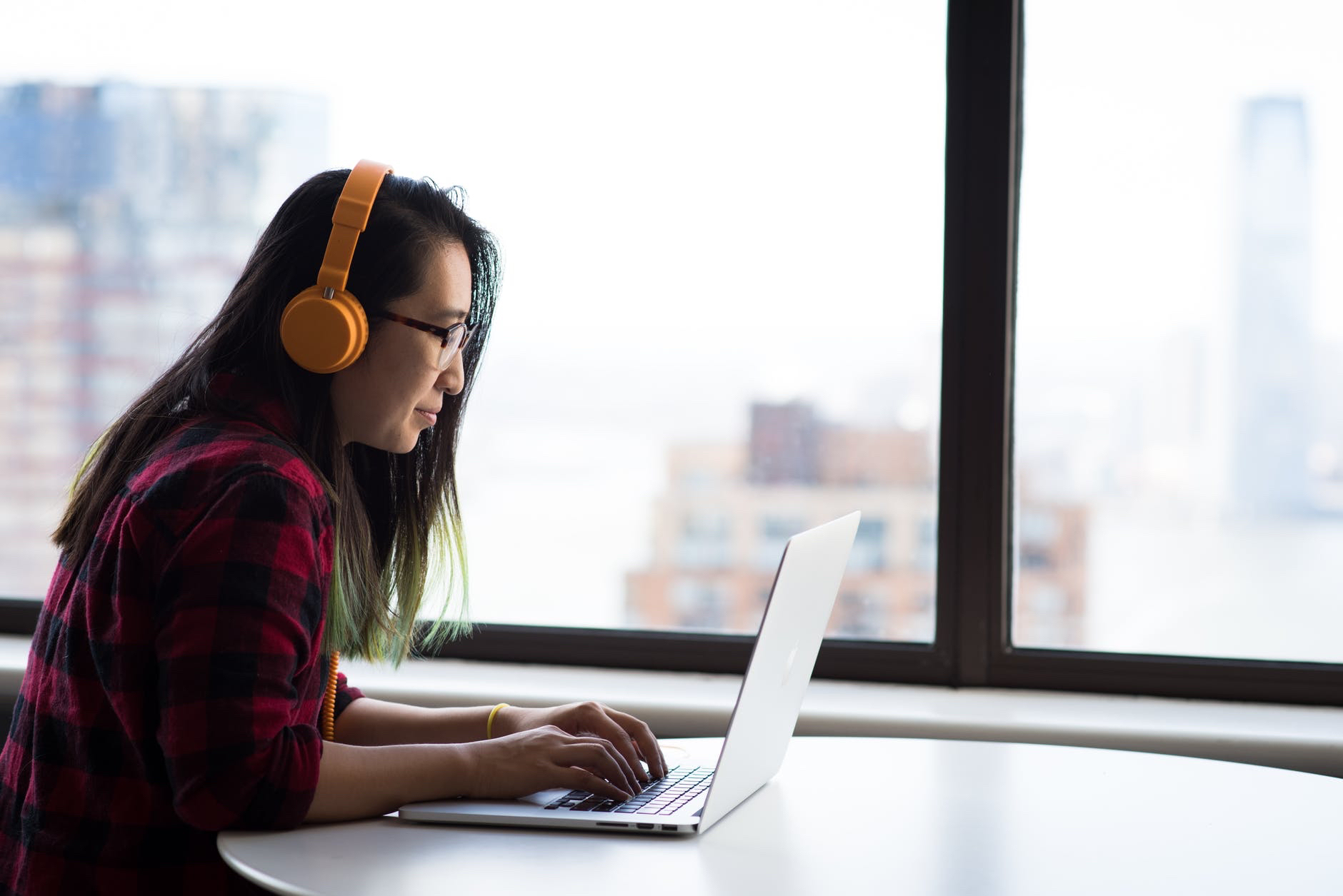 Real-time remote learning. Woman in front of laptop wearing headphones .