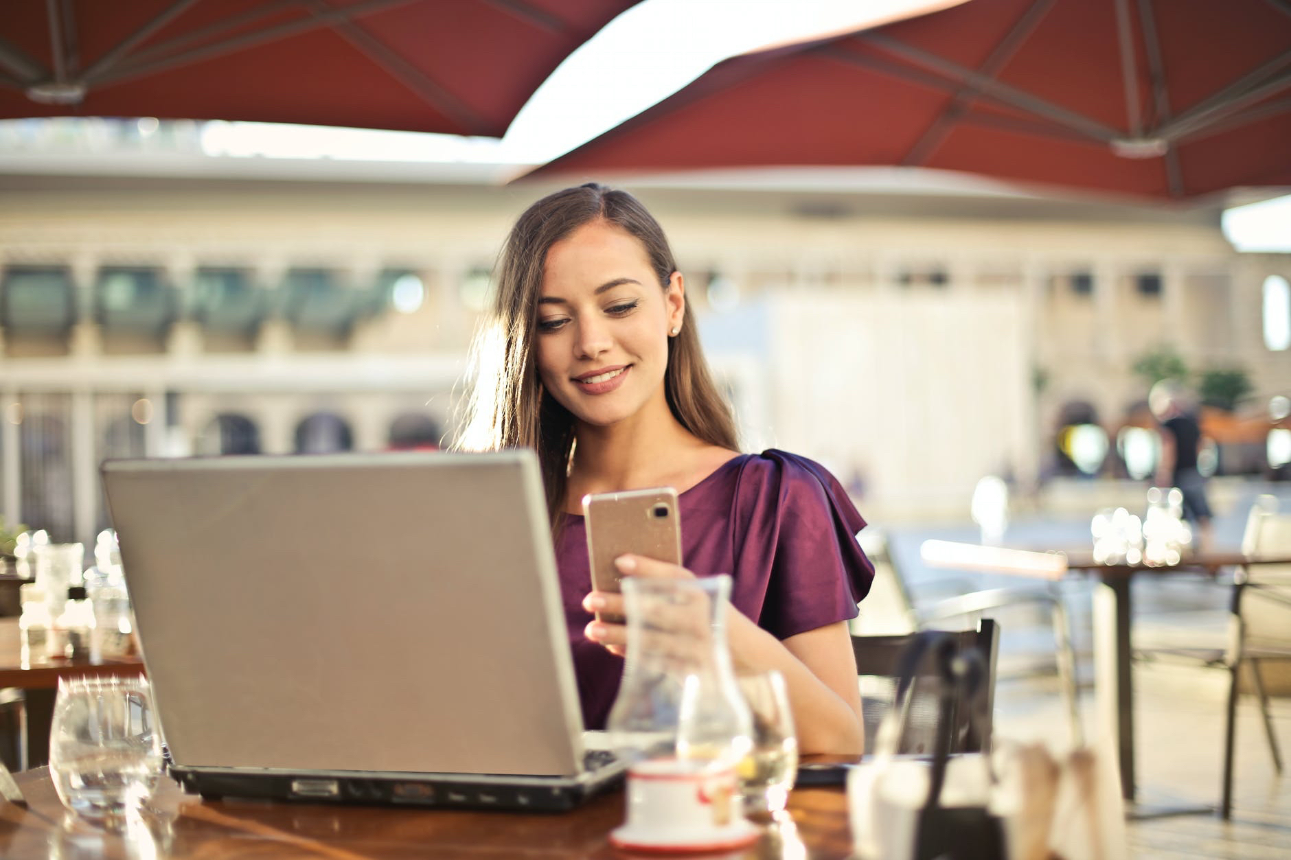 Woman with laptop open and holding smartphone.