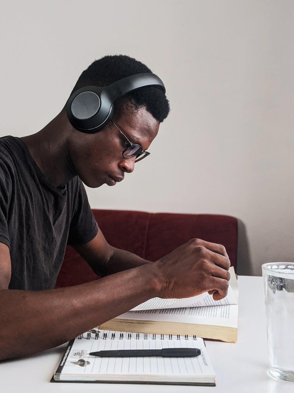 Black man studying with headphones and book.