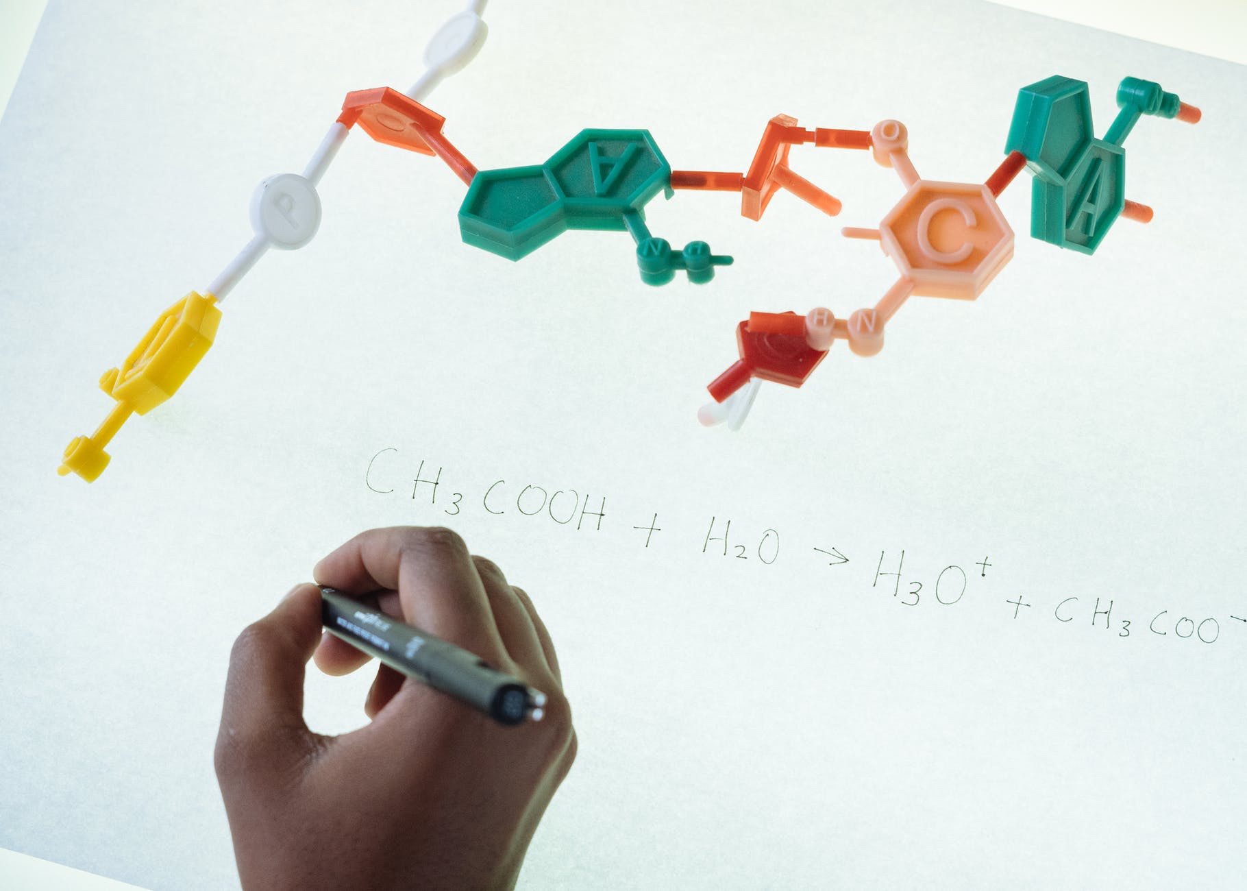 Chemistry classes online. Hand writing on paper next to chemistry models.