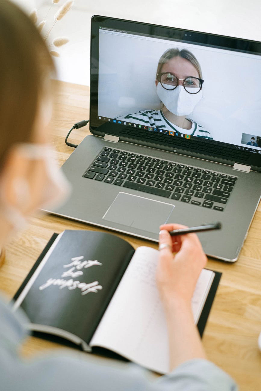 Telehealth session with female doctor wearing mask on laptop screen.