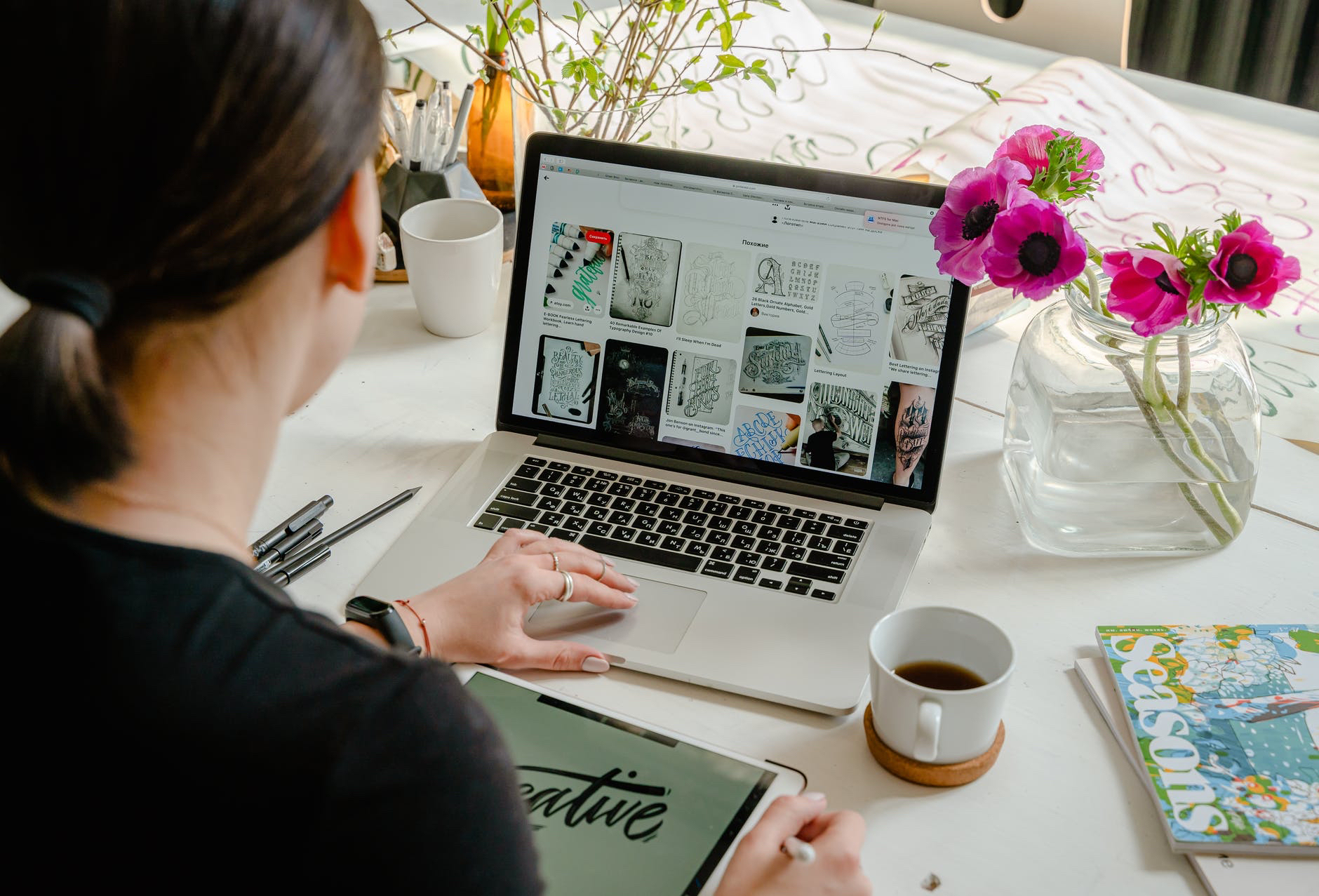 Back of woman with dark hair and ponytail using laptop. Screen has several images.