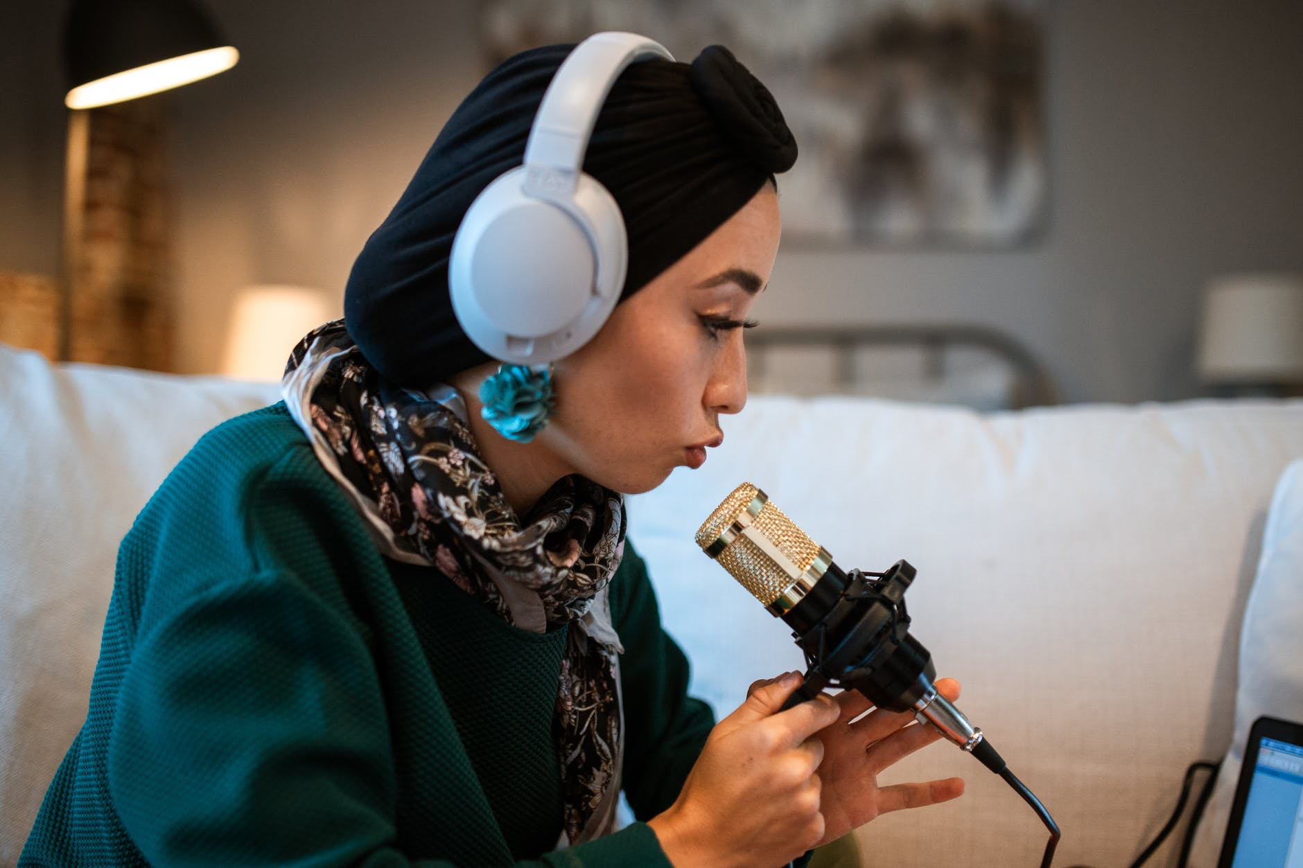 Woman wearing headphones leaning toward microphone.