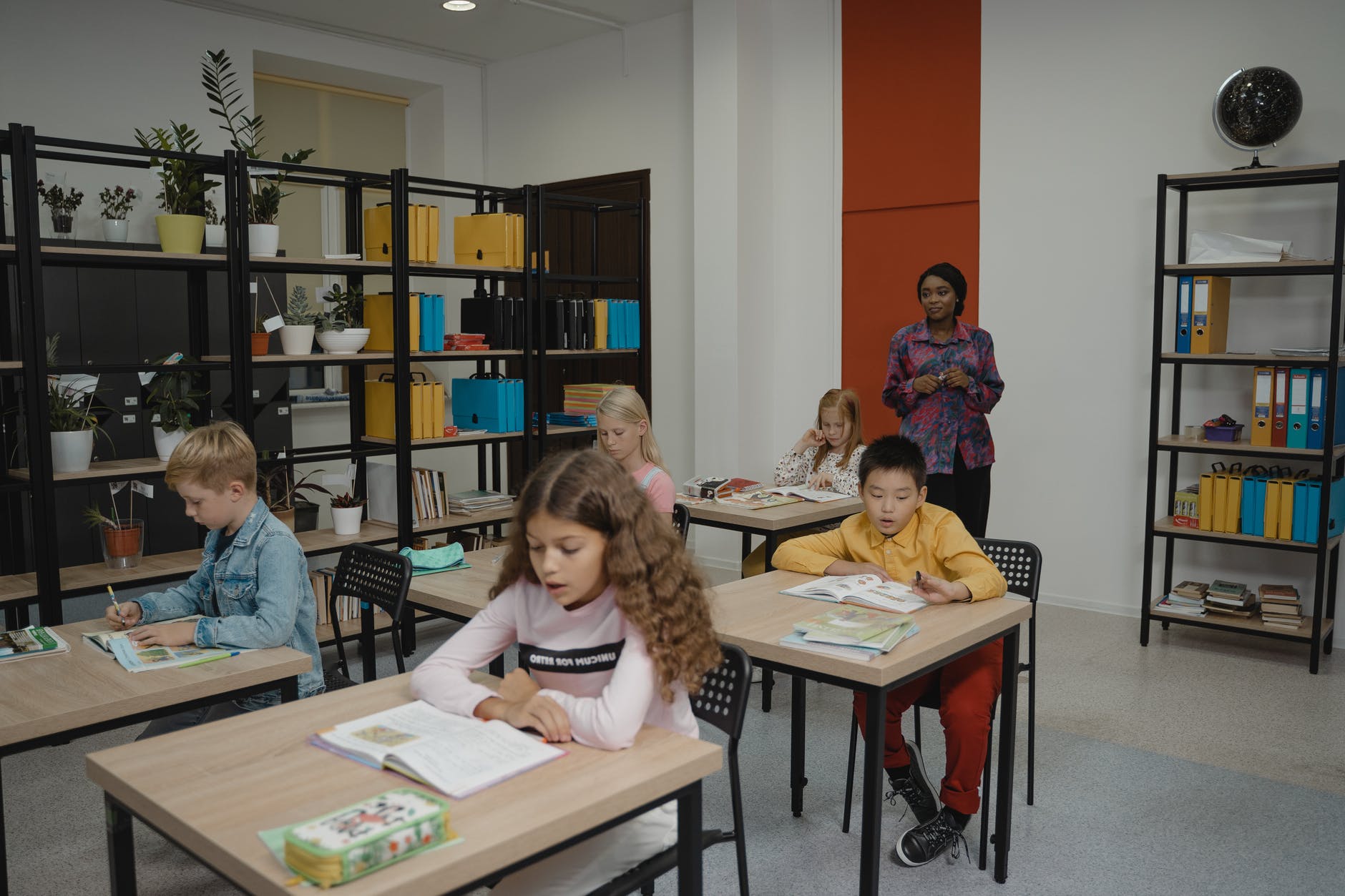 Elementary school teacher and students at desks.