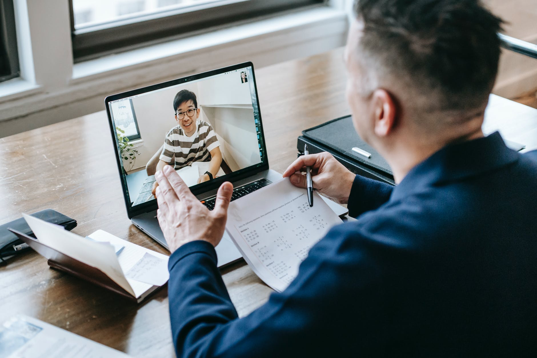 Instructor communicating with student via laptop and video chat.