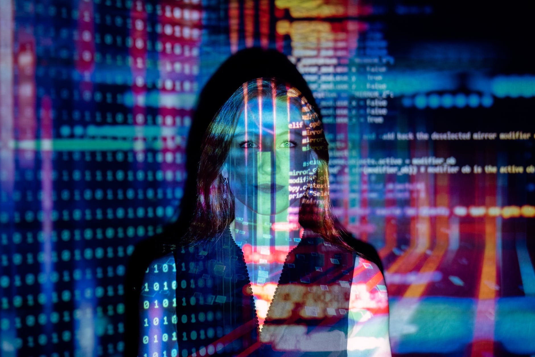 Woman with long hair and colorful sequences projected on face.