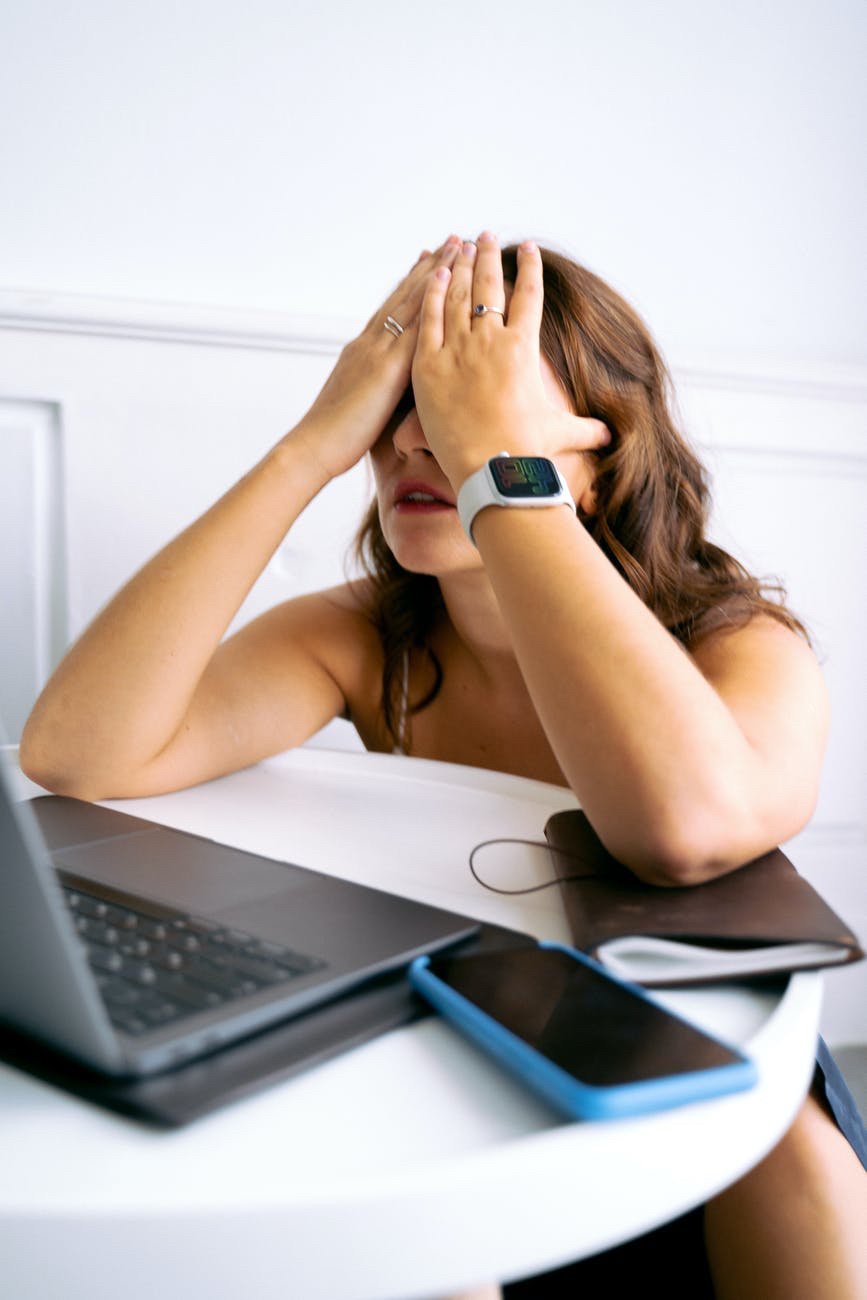 Woman with hands on face in front of laptop