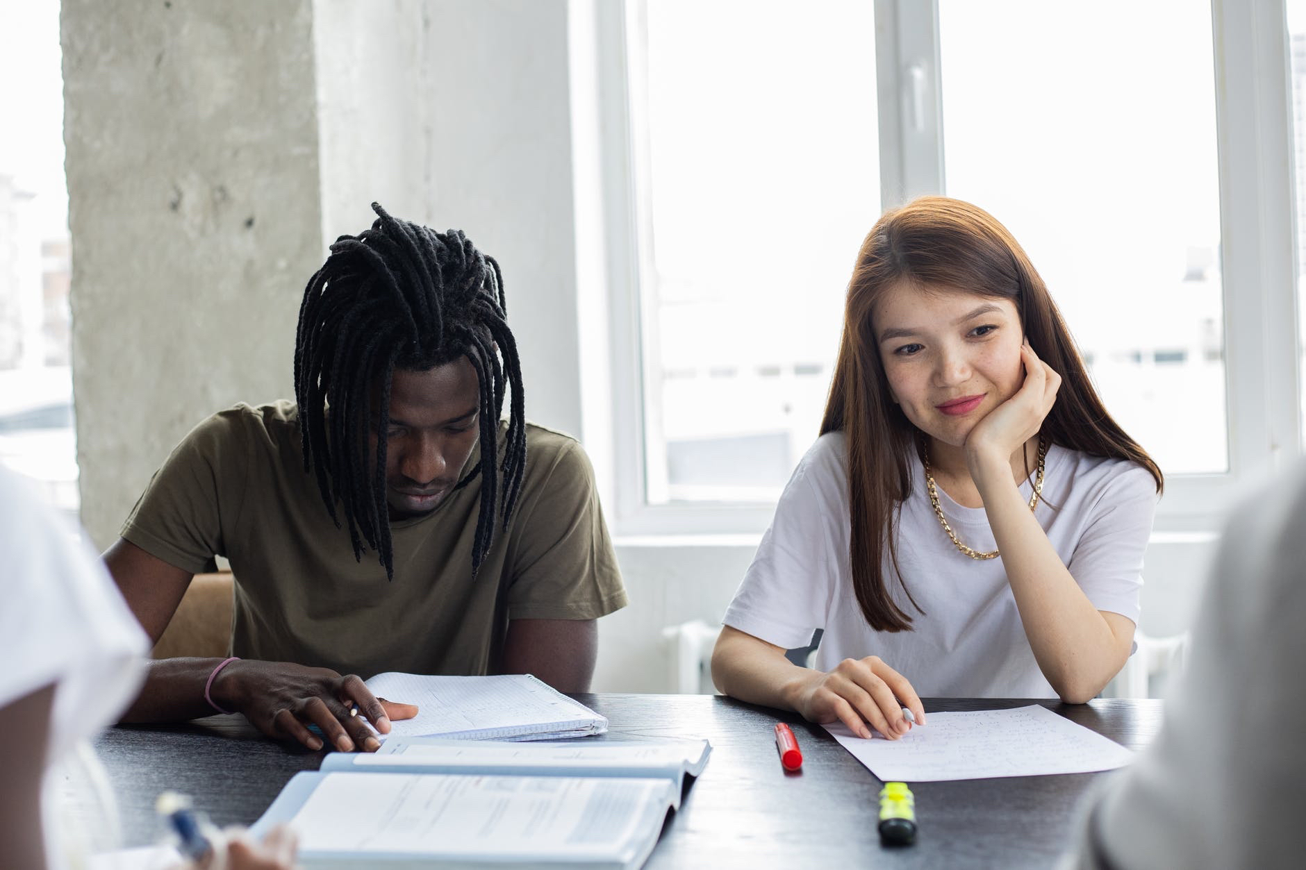 Black male student and brunette  white female studying at desk.