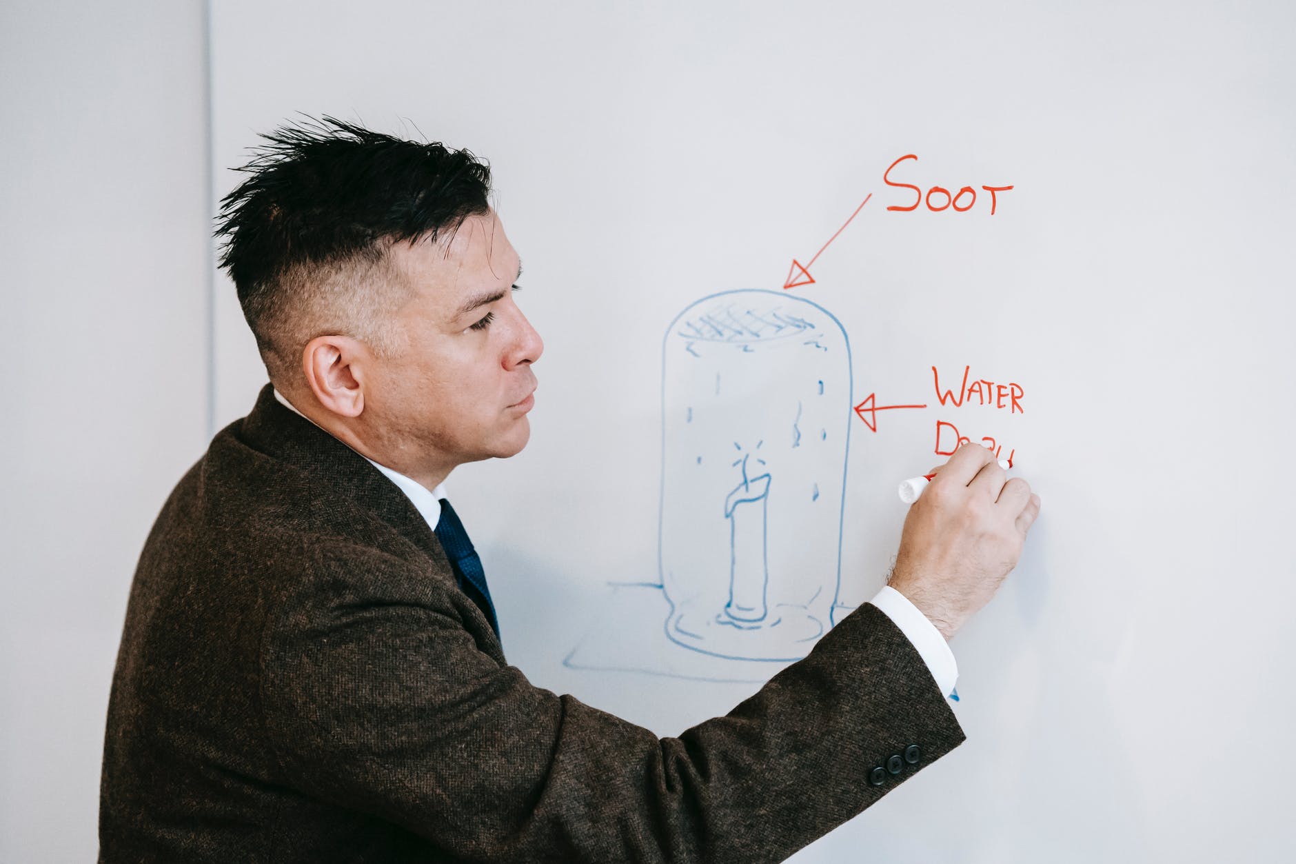 Latinx male professor writing on whiteboard.