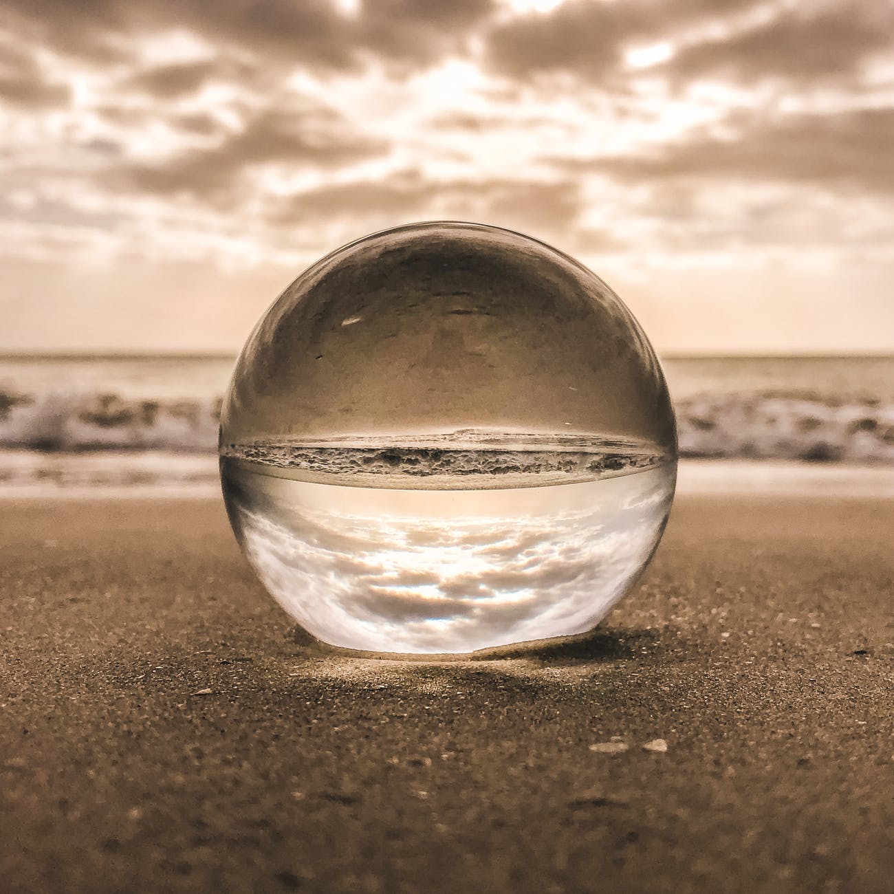 Sand and glass sphere on beach.