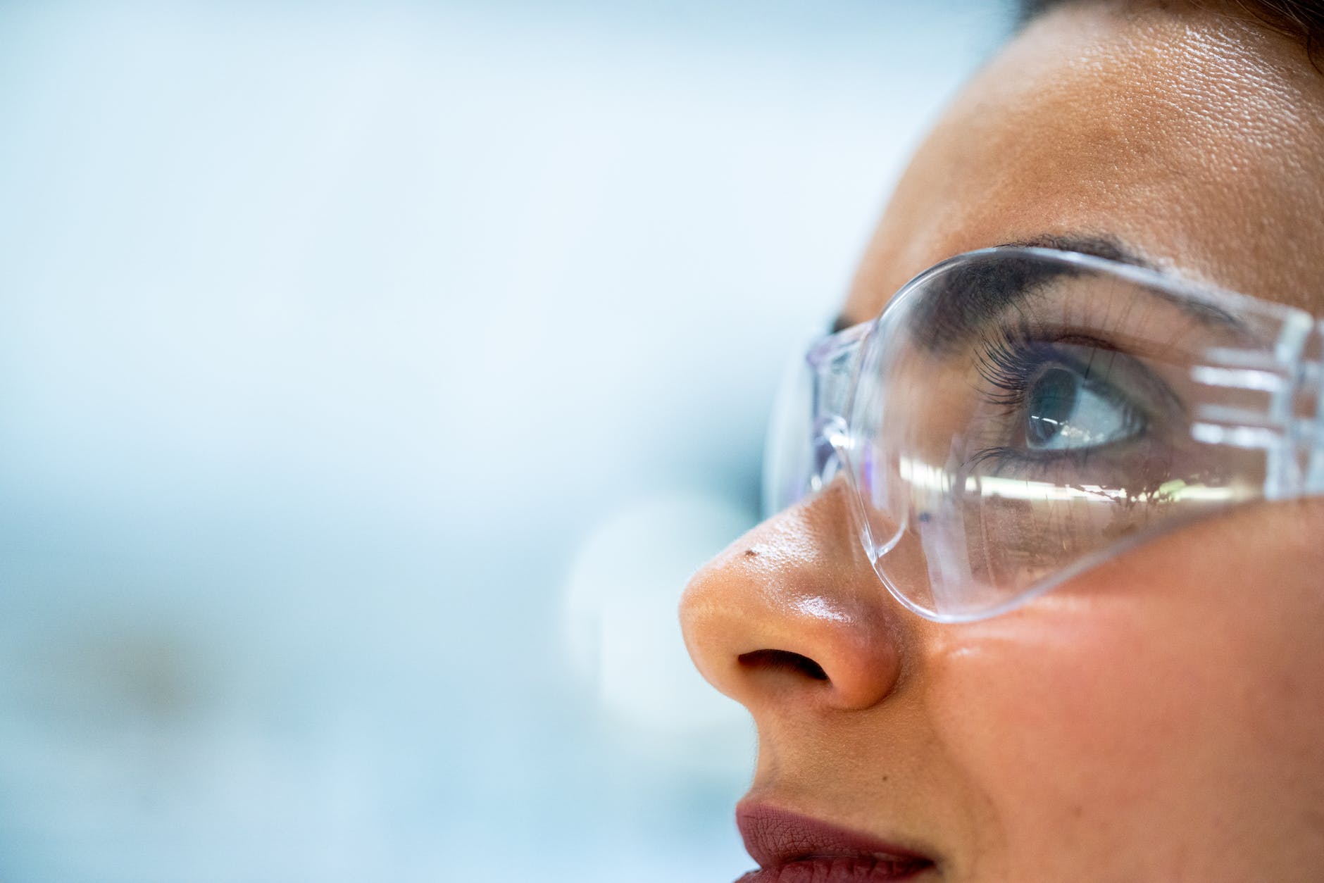Face of woman wearing protective eyeglasses. Brown skin and dark eyes.