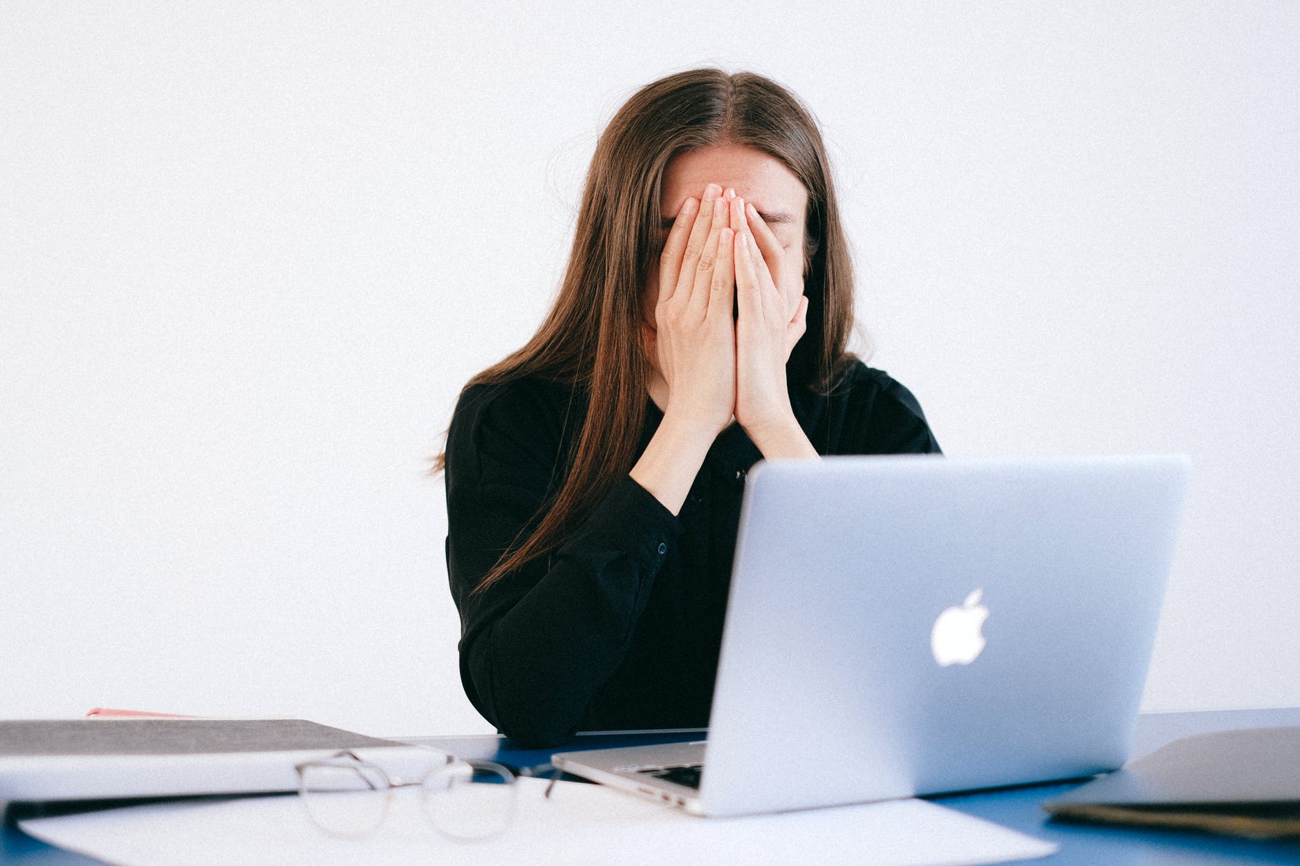 Woman with hands on face in front of laptop.
