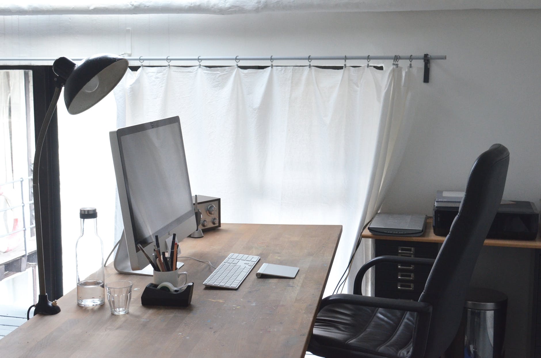 Desktop computer with large monitor and keyboard on the desk with empty chair.
