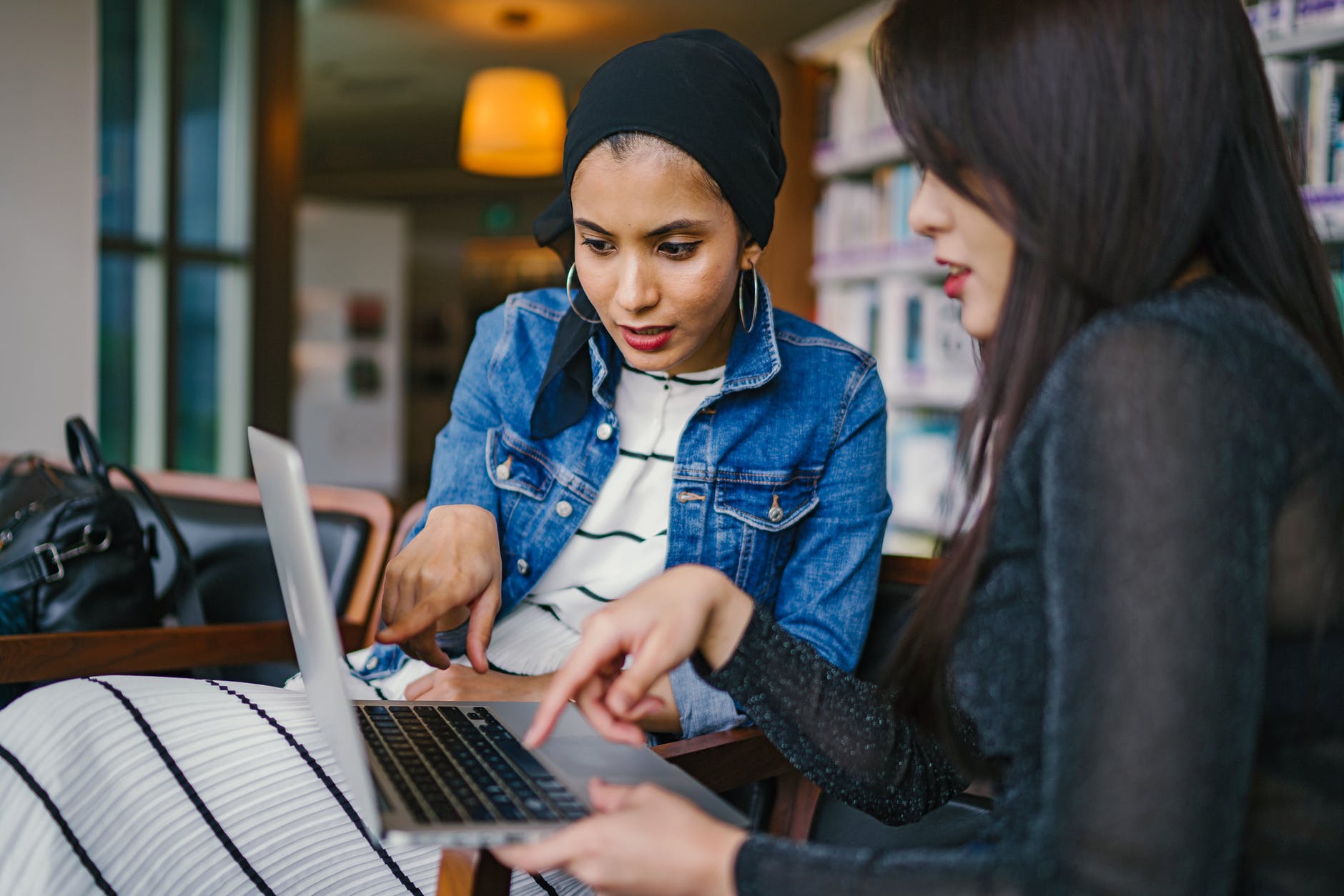 Two women pointing at laptop.