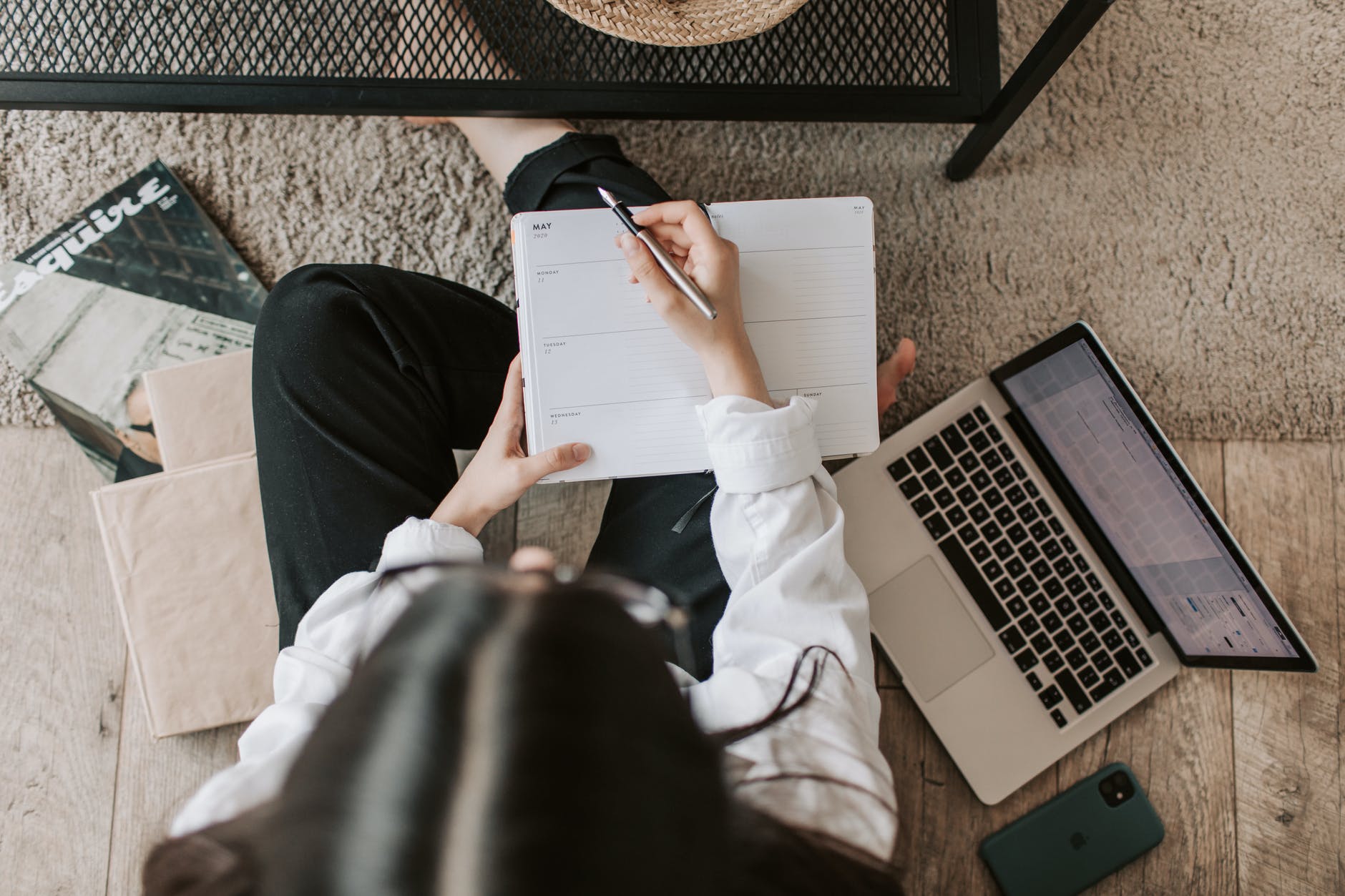 A hand holding a pen and an open laptop.
