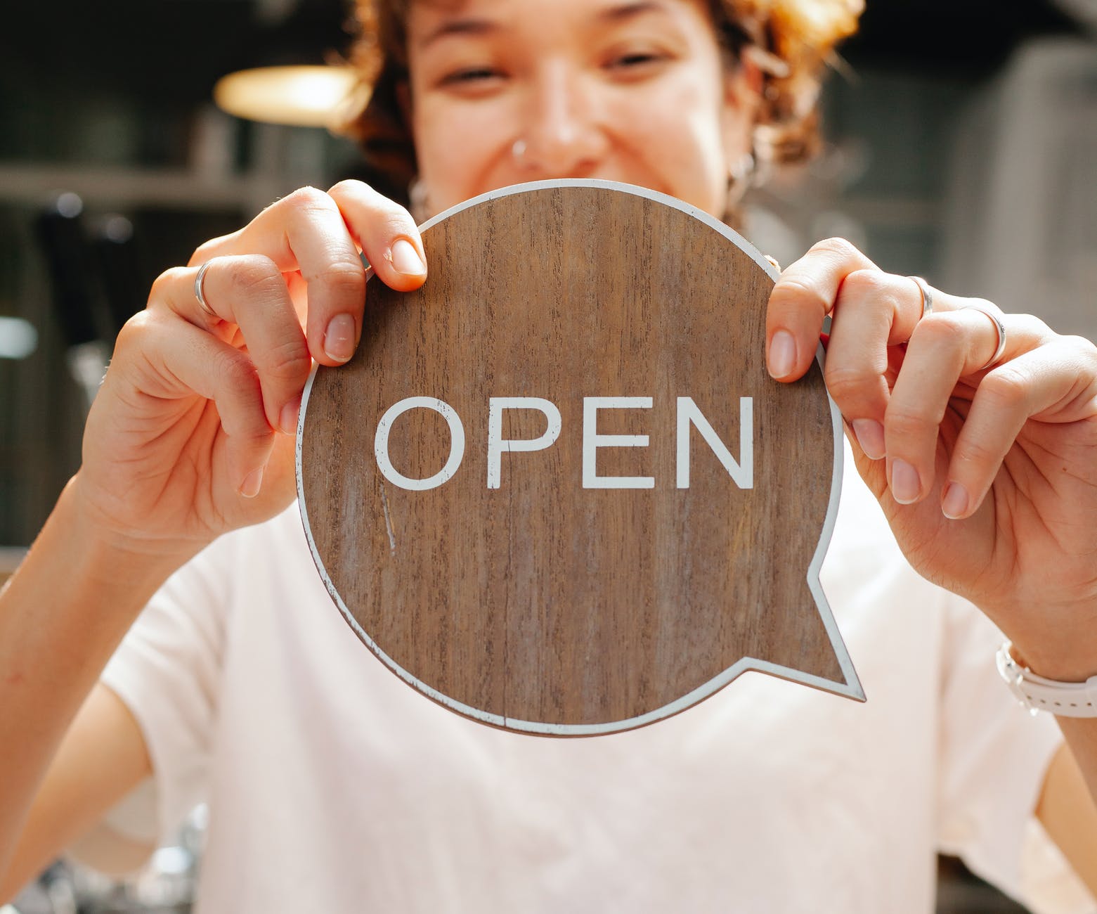 Woman holding callout shaped paper that says "Open"