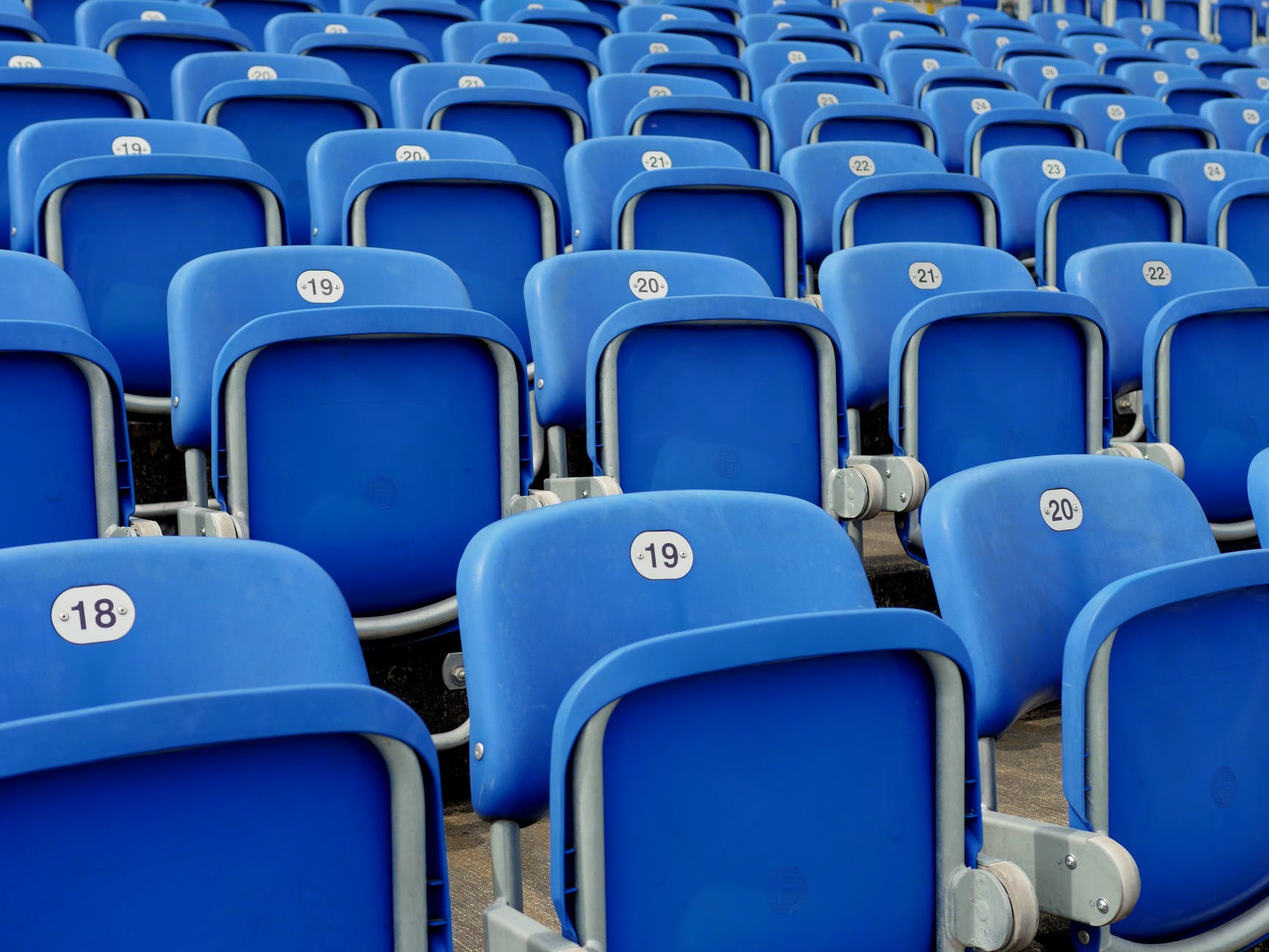 Blue foldable lecture hall seats or seats at an athletic complex. All sets are numbered.