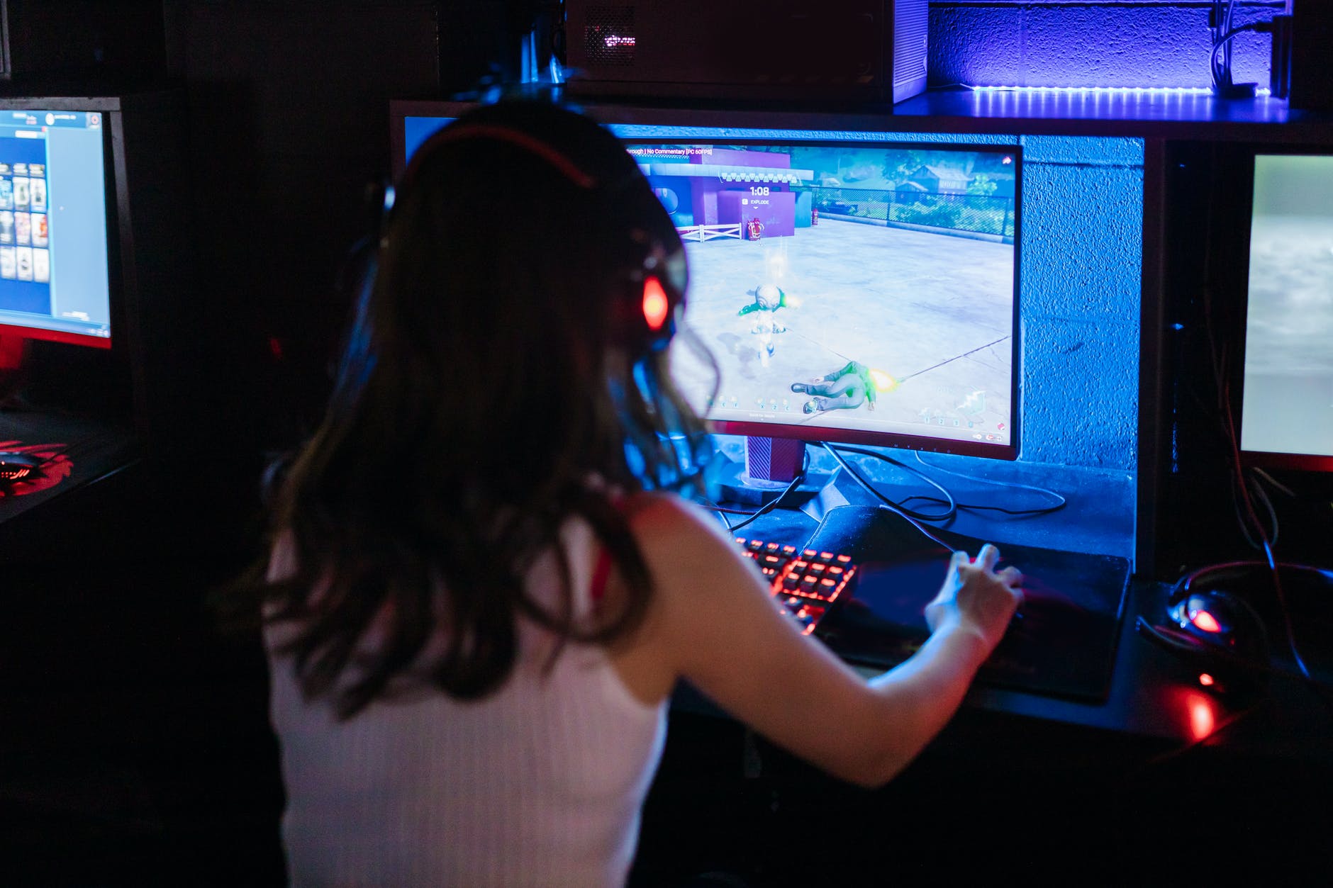 Monitor with game and person with long hair facing screen with back toward camera.