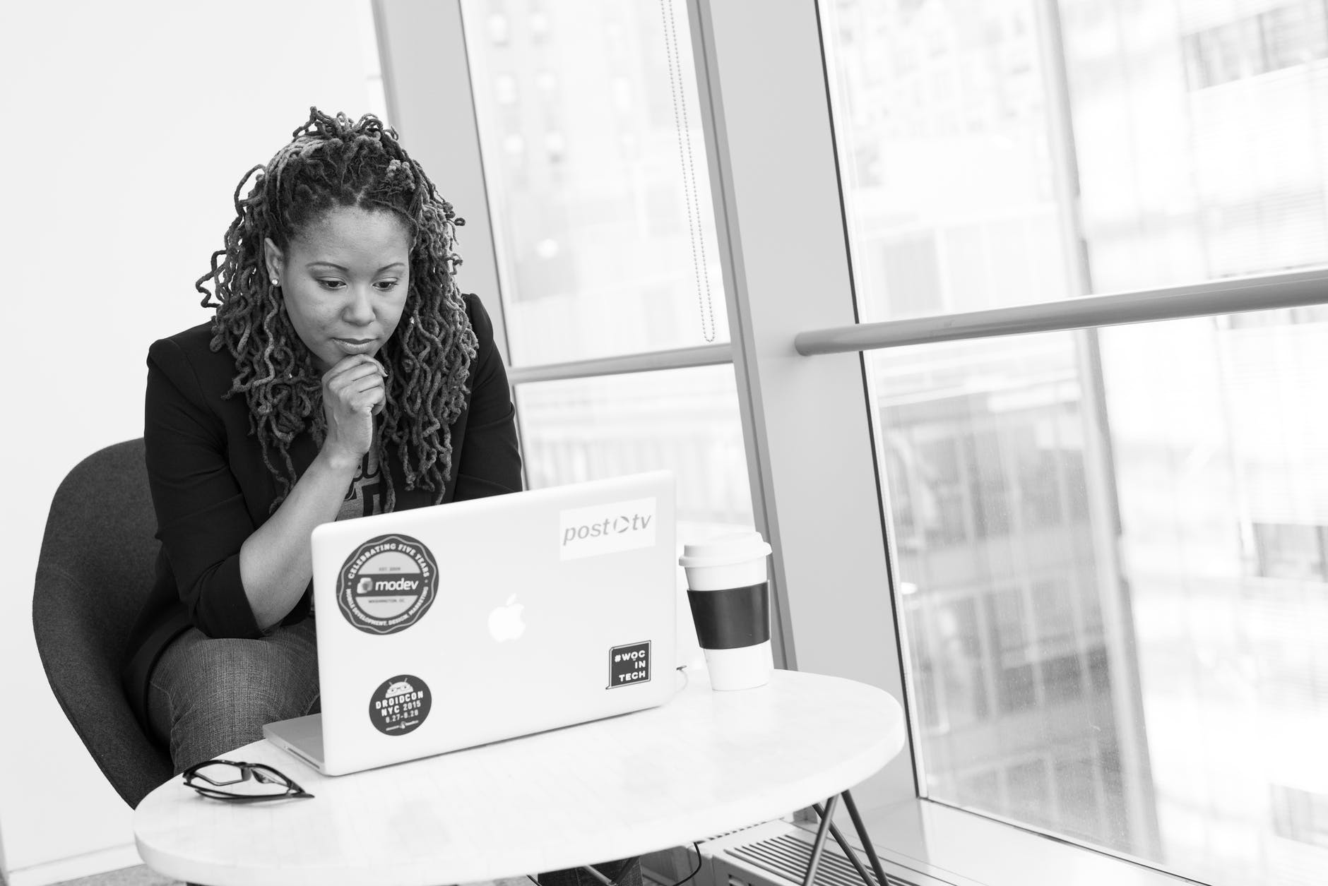 Woman seated at coffee table working on laptop with coffee cup.
