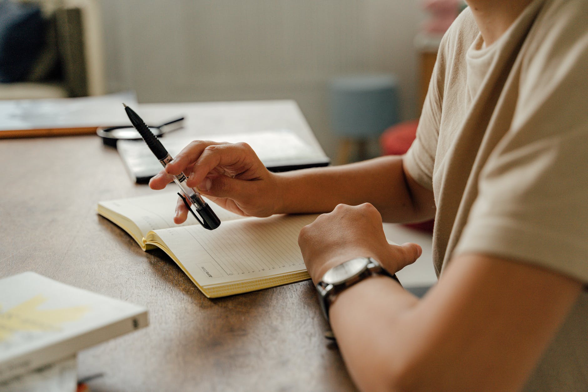 Hand holding pen over notebook.
