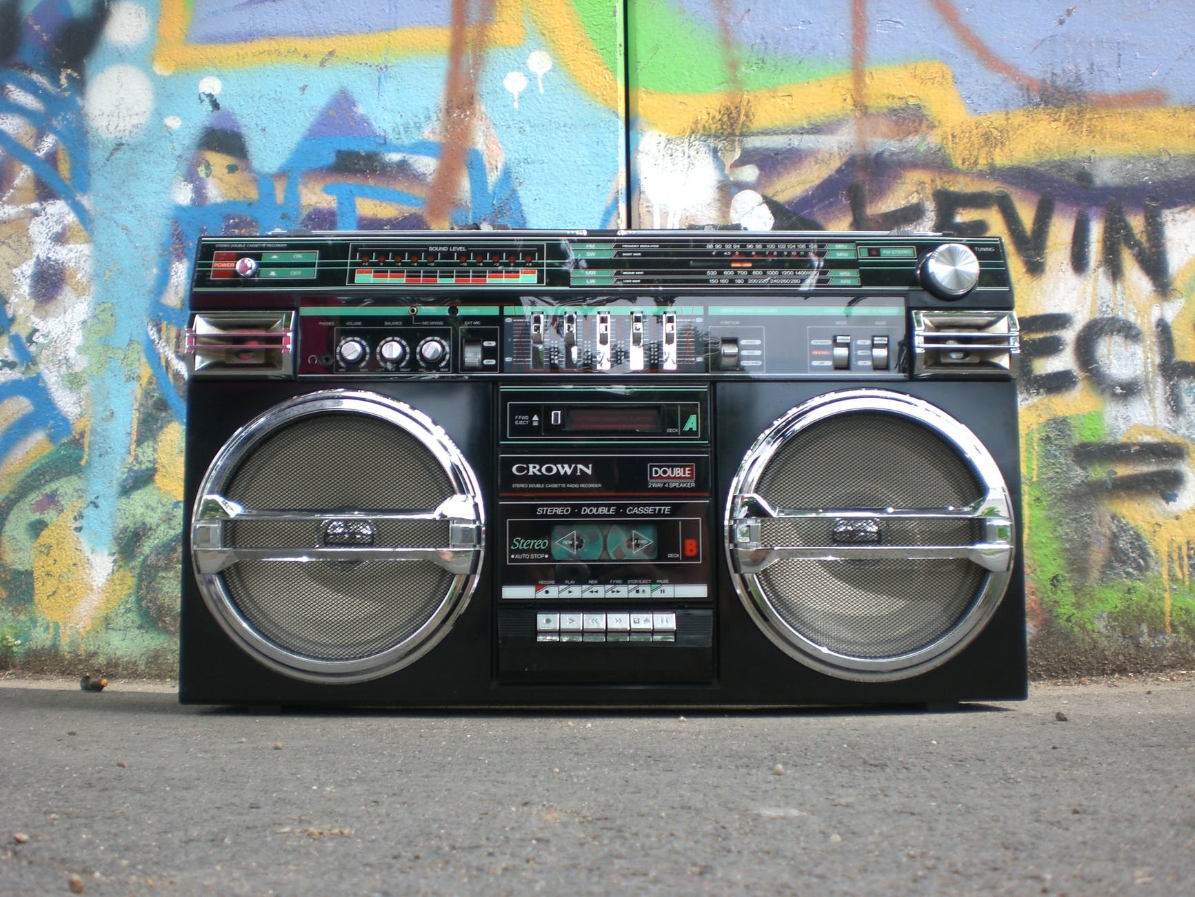 Boombox on ground next to wall full of street art.