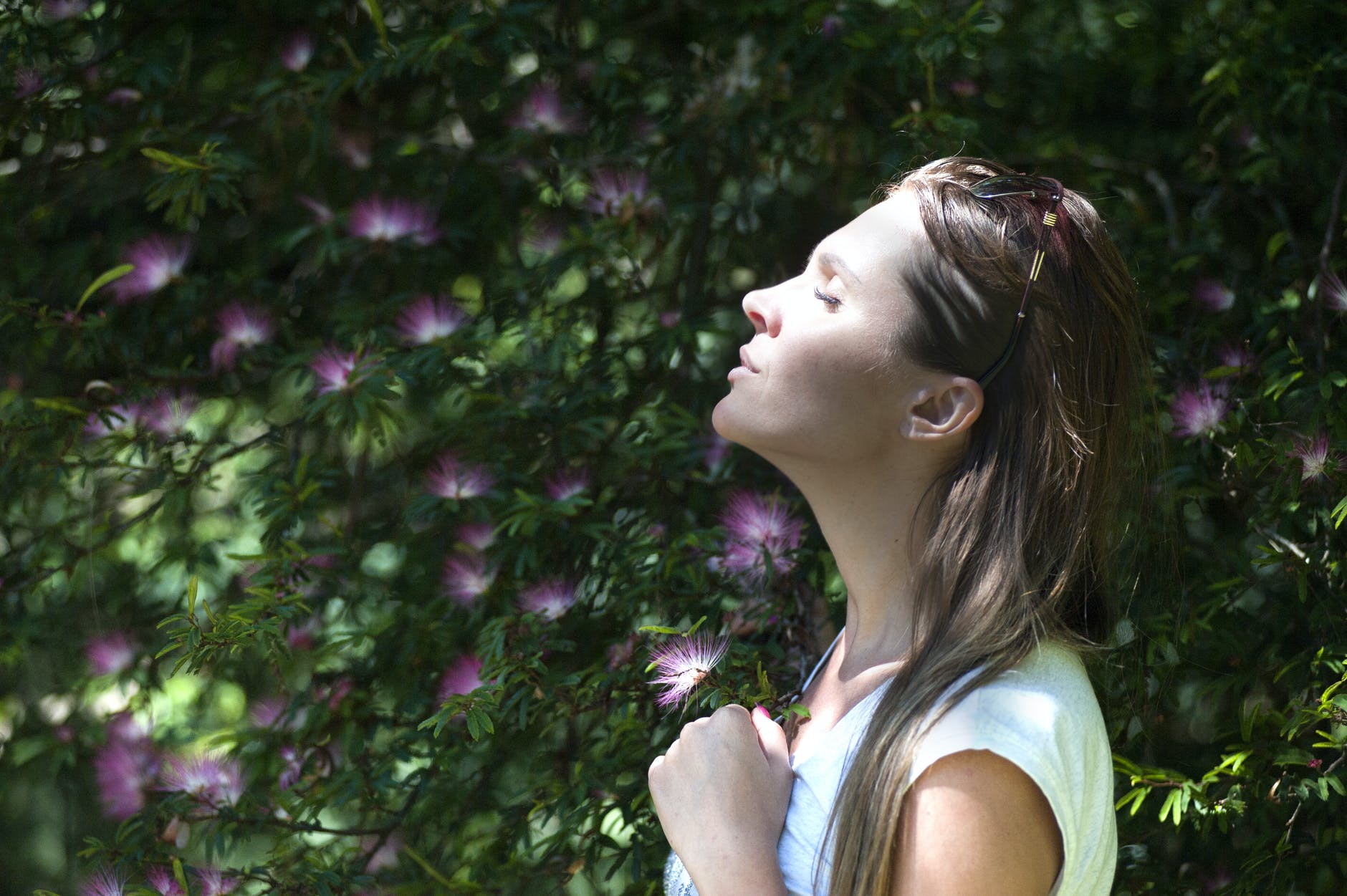 Woman outside smelling flowers.