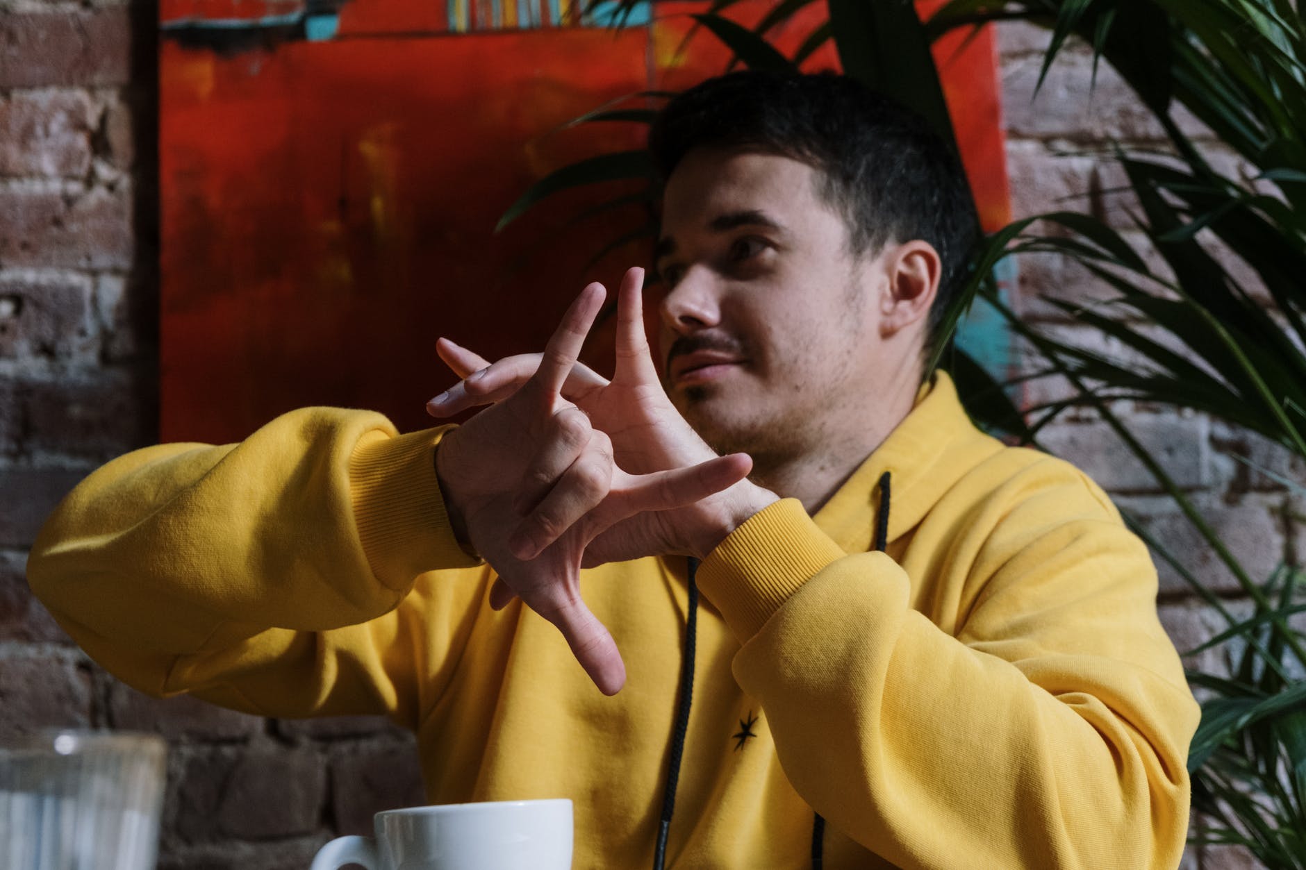 Man wearing yellow hoodie using sign language.