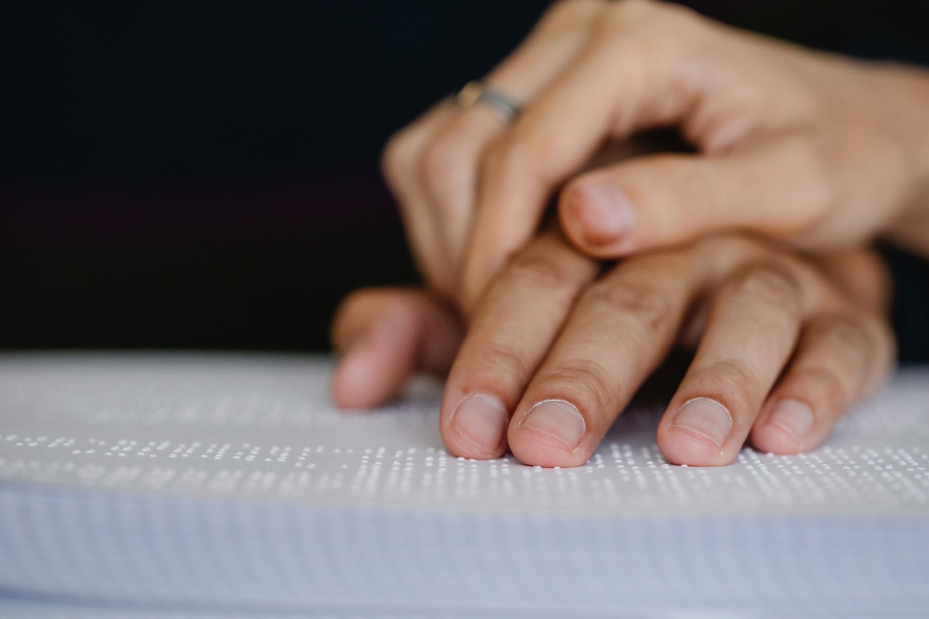 Hand over another hand feeling Braille paper.