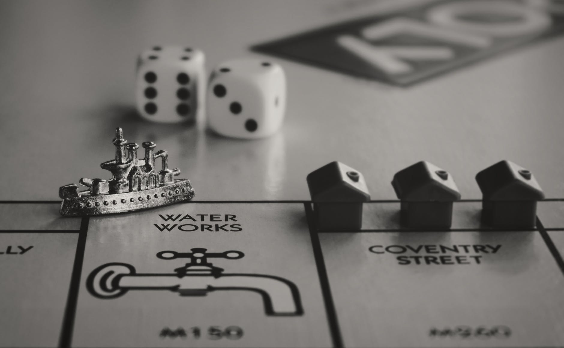 Black and white image of monopoly board with dice and tokens.