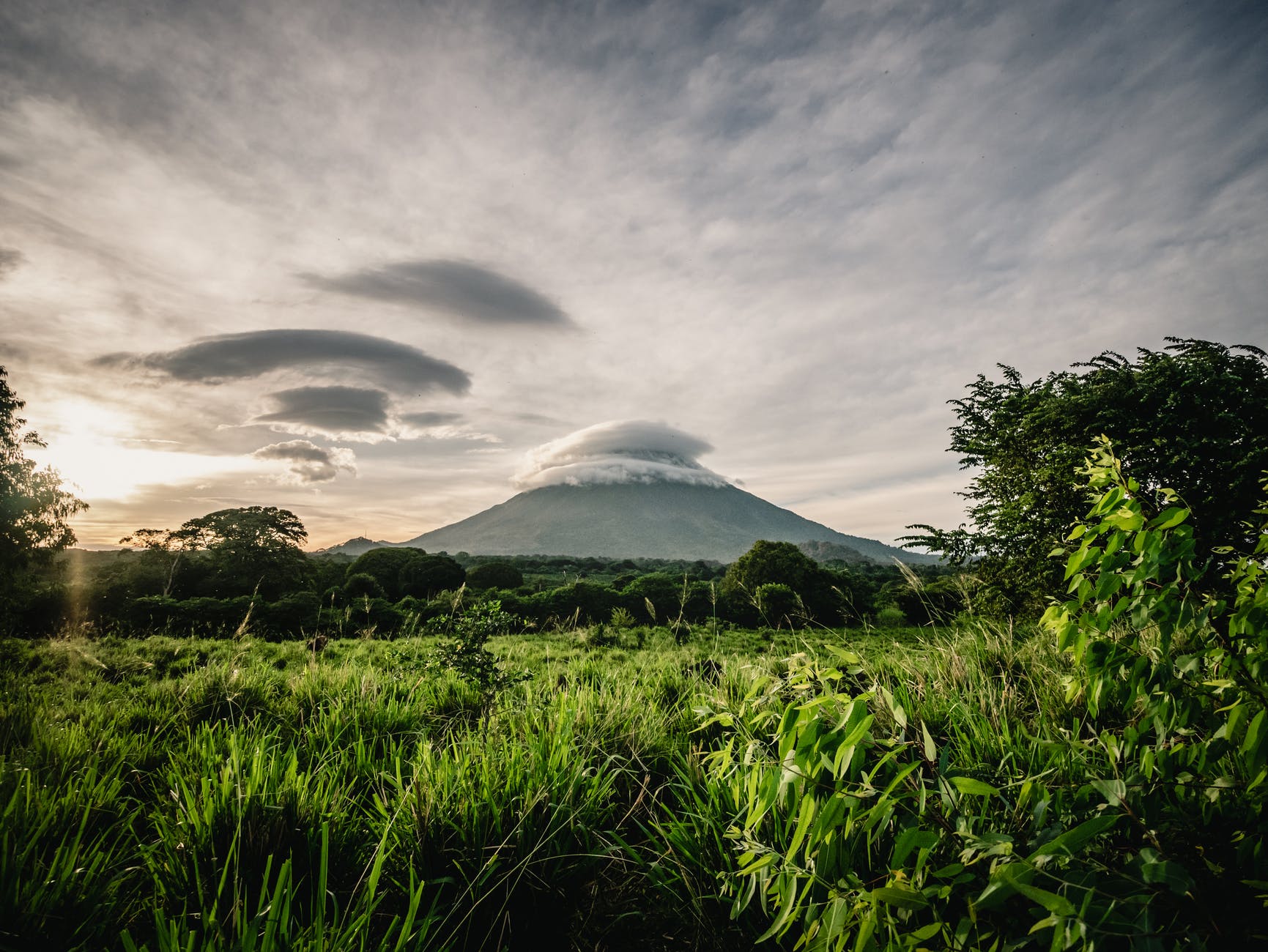 Lush vegetation and volcano in the distance. Cloudy skies.