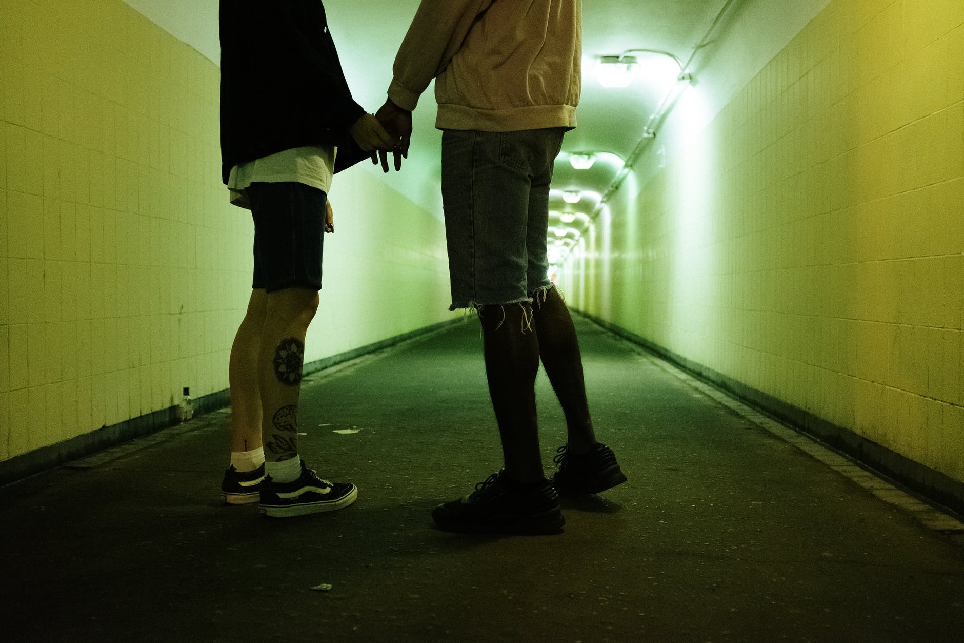 Two people holding hands in tunnel.