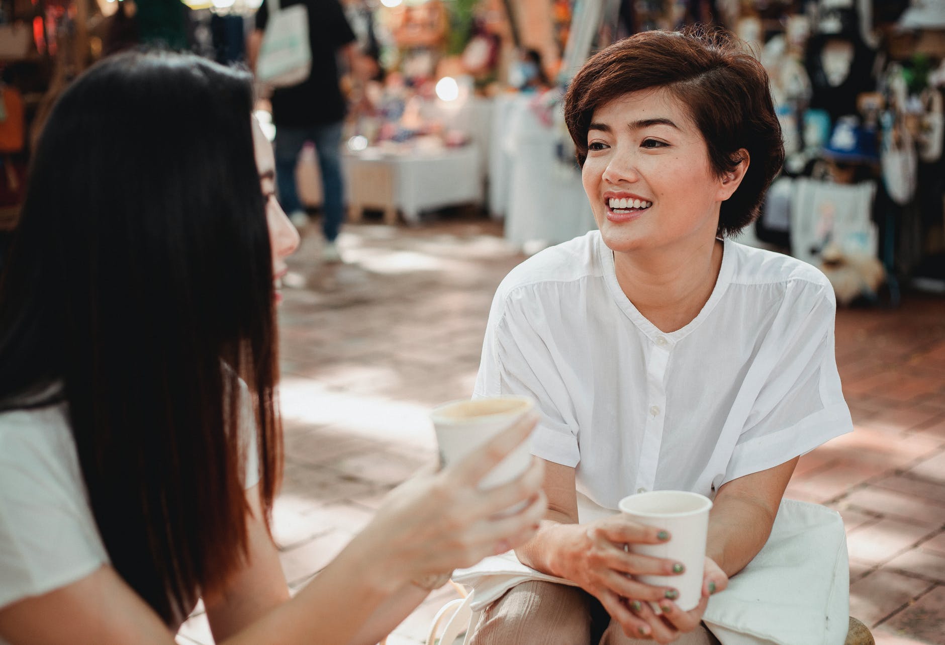 Two women with coffee cups facing each other and talking.