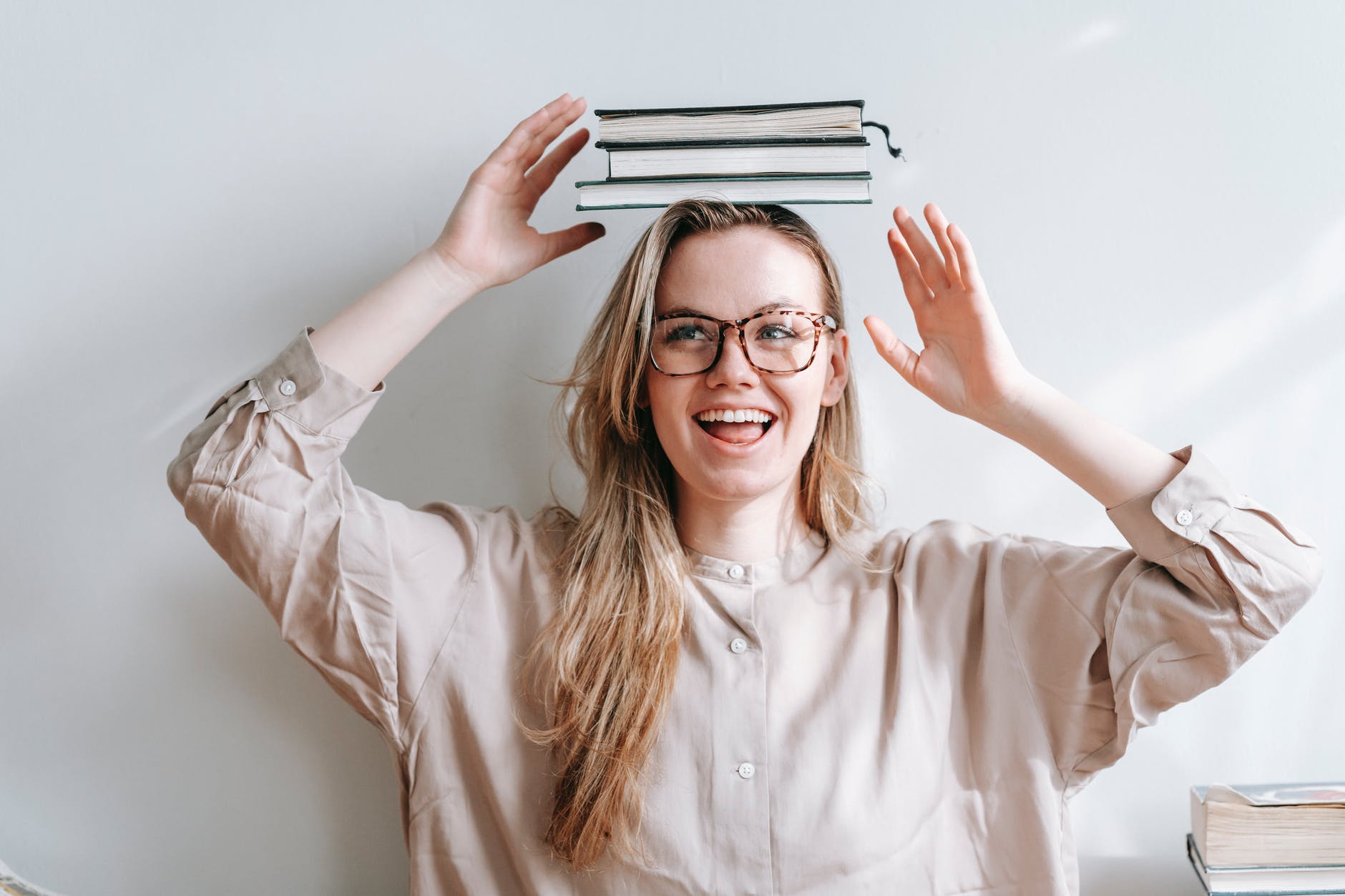 Woman with blond long hair wearing glasses and balancing book on head.