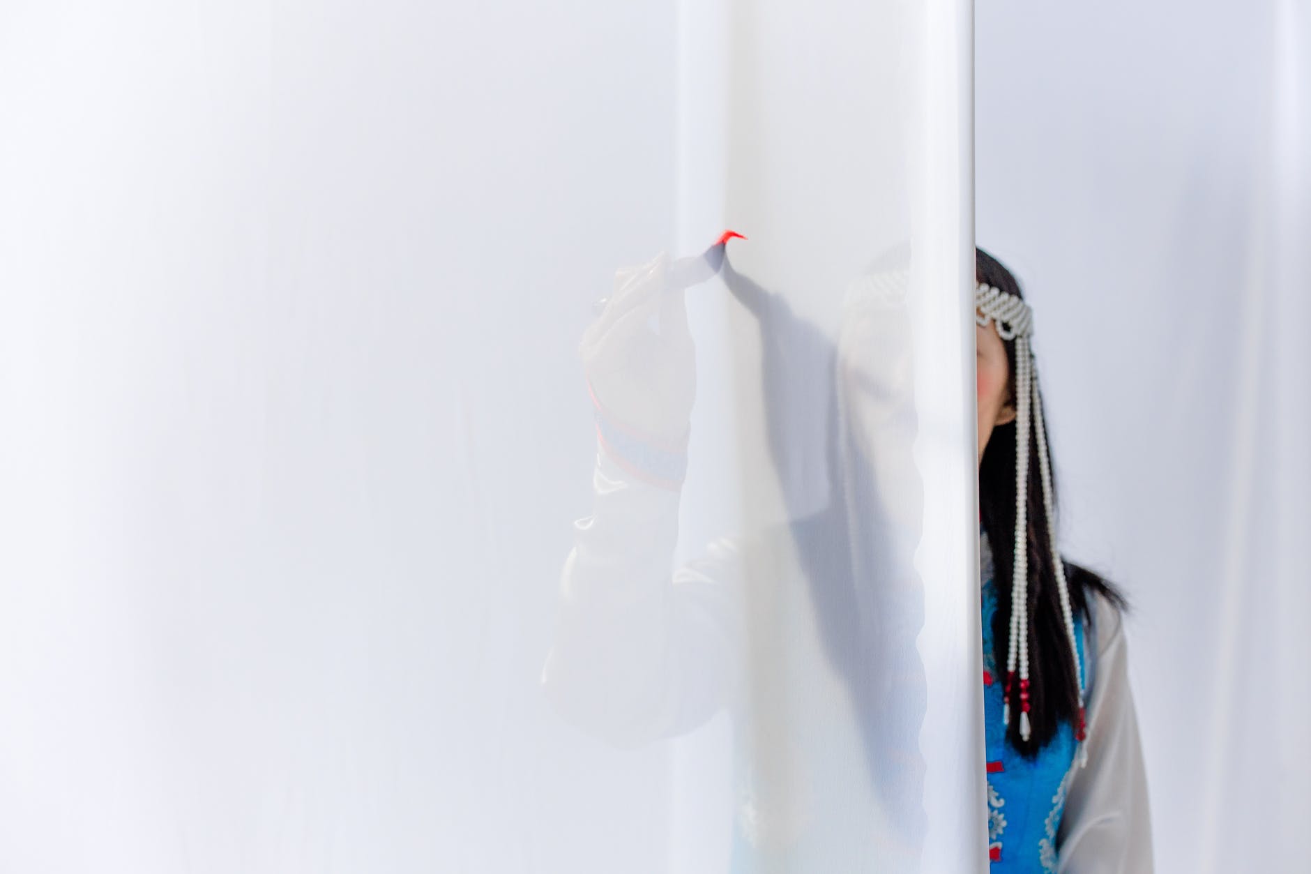woman behind fabric. Woman has black long hair.