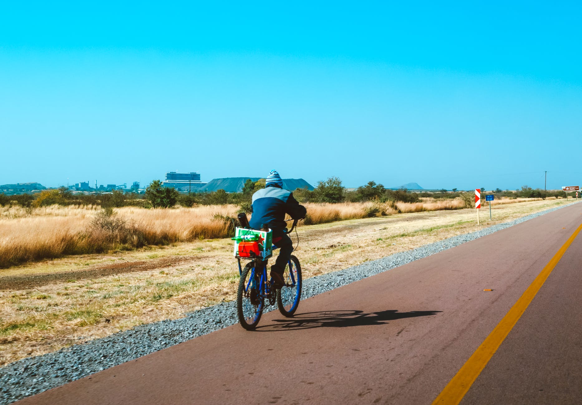 Person on bicycle on left lane of flat road. Mountains can be see in the distance.