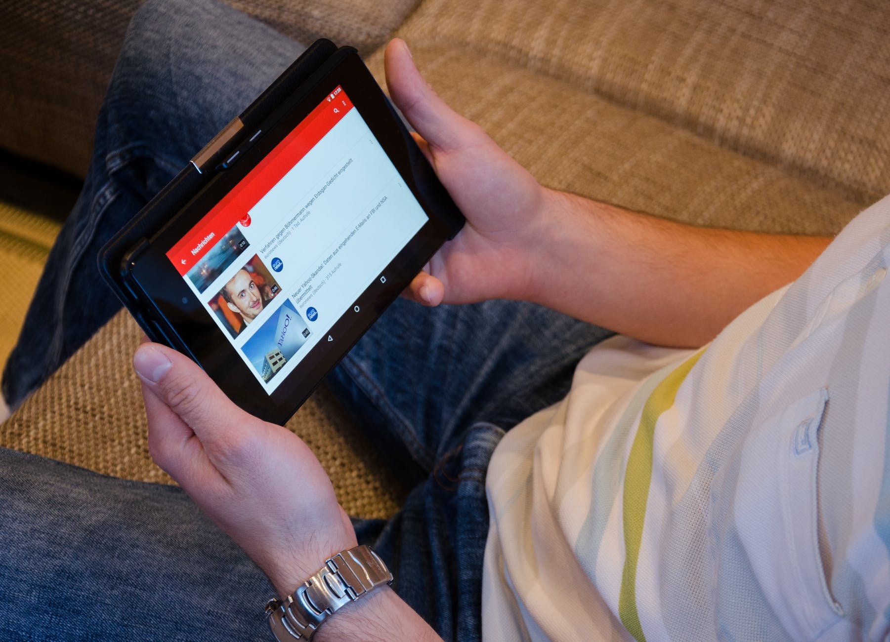 Hands holding tablet with YouTube screen.