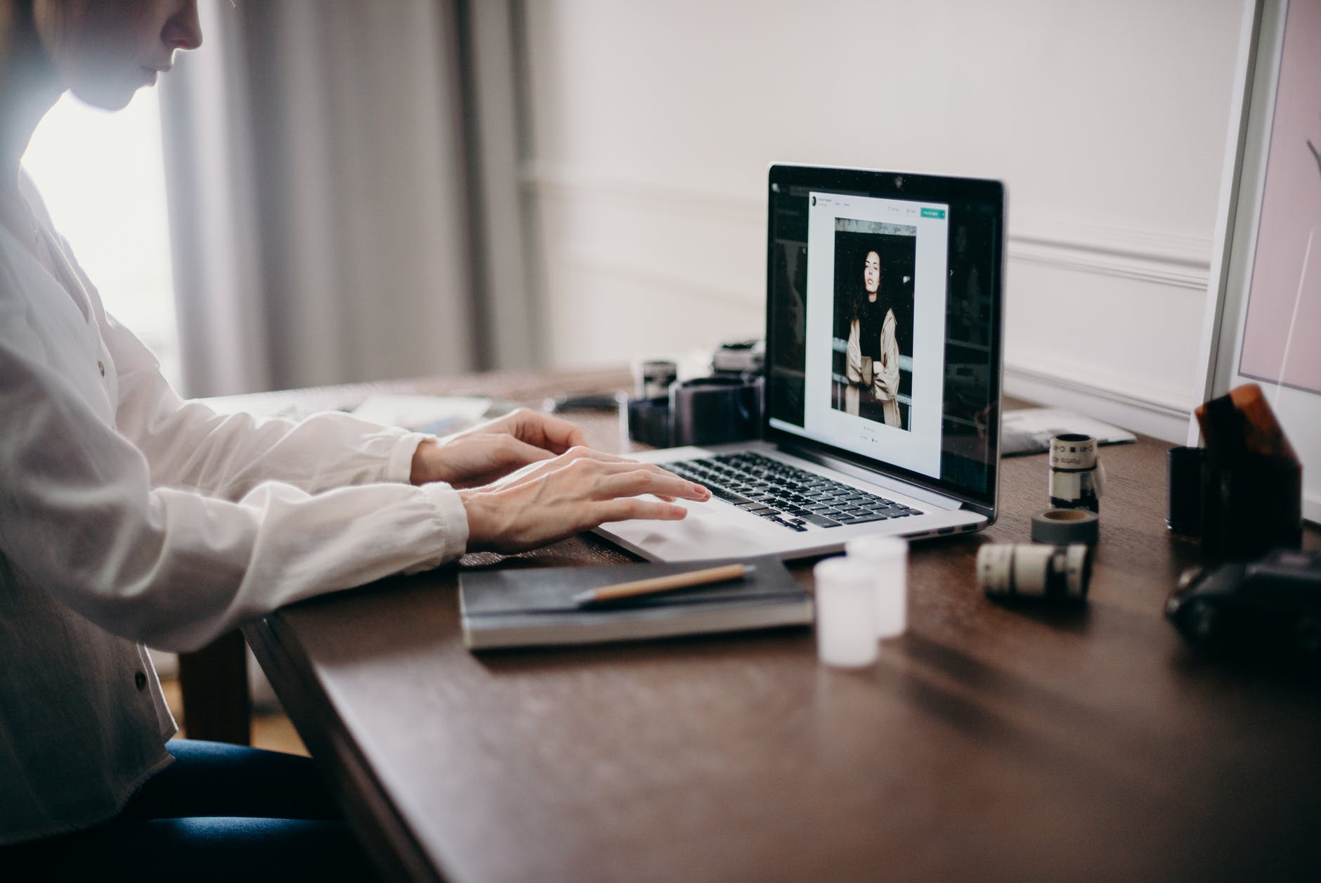Laptop with photo on screen. Hands are typing on keyboard.