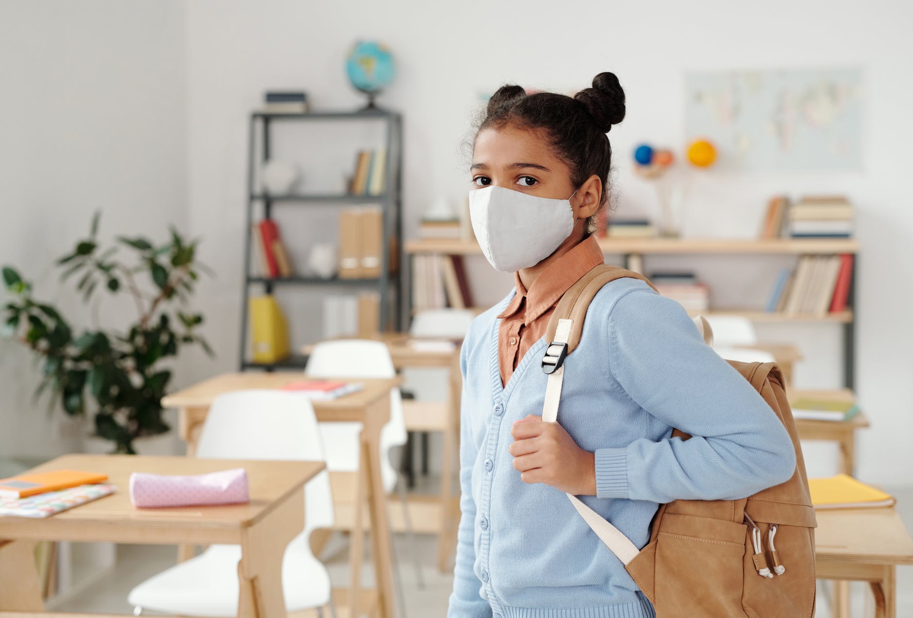Girl with backpack in classroom. 