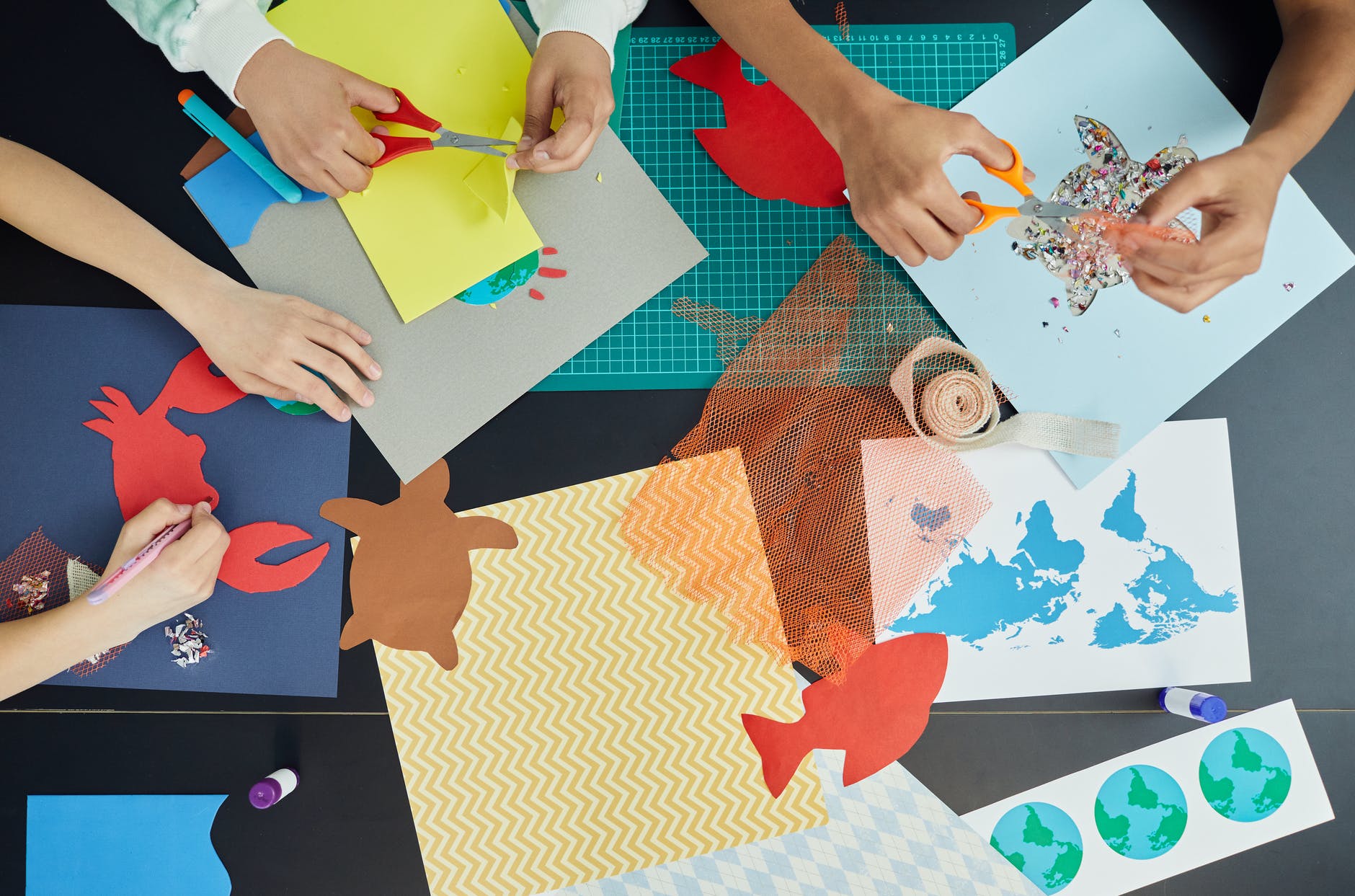 Top down view of table with colorful paper cut outs of fish and turtles.