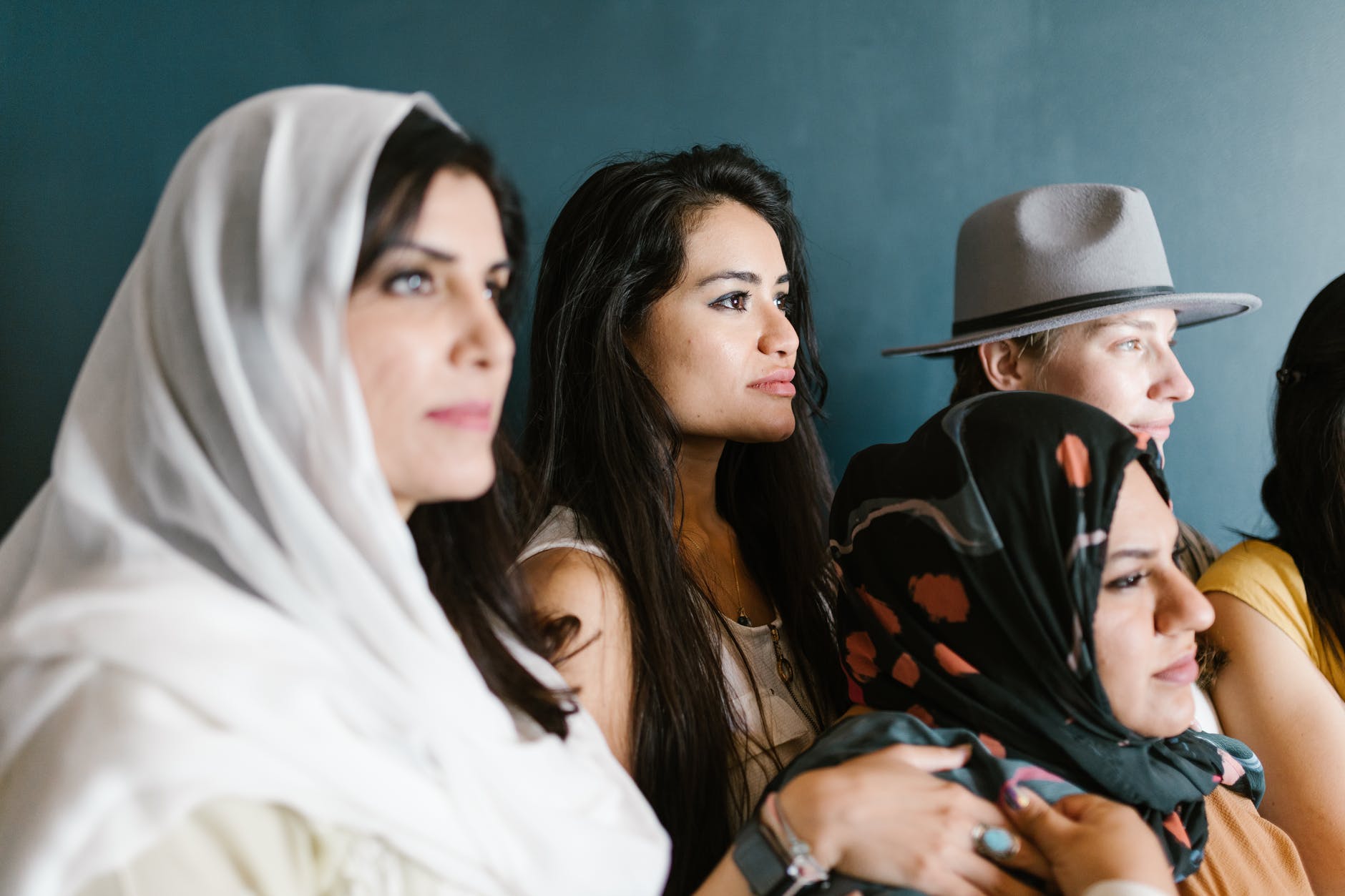 Women looking to the right. Some are wearing headscarves and hats.