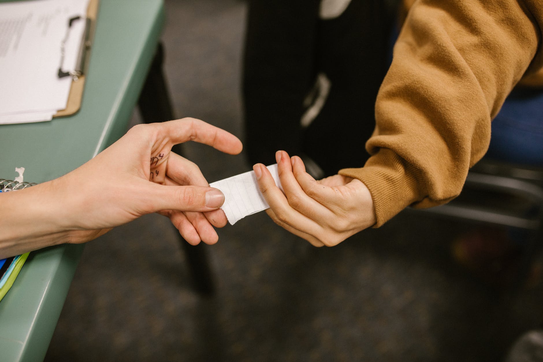 Two hands passing a paper note