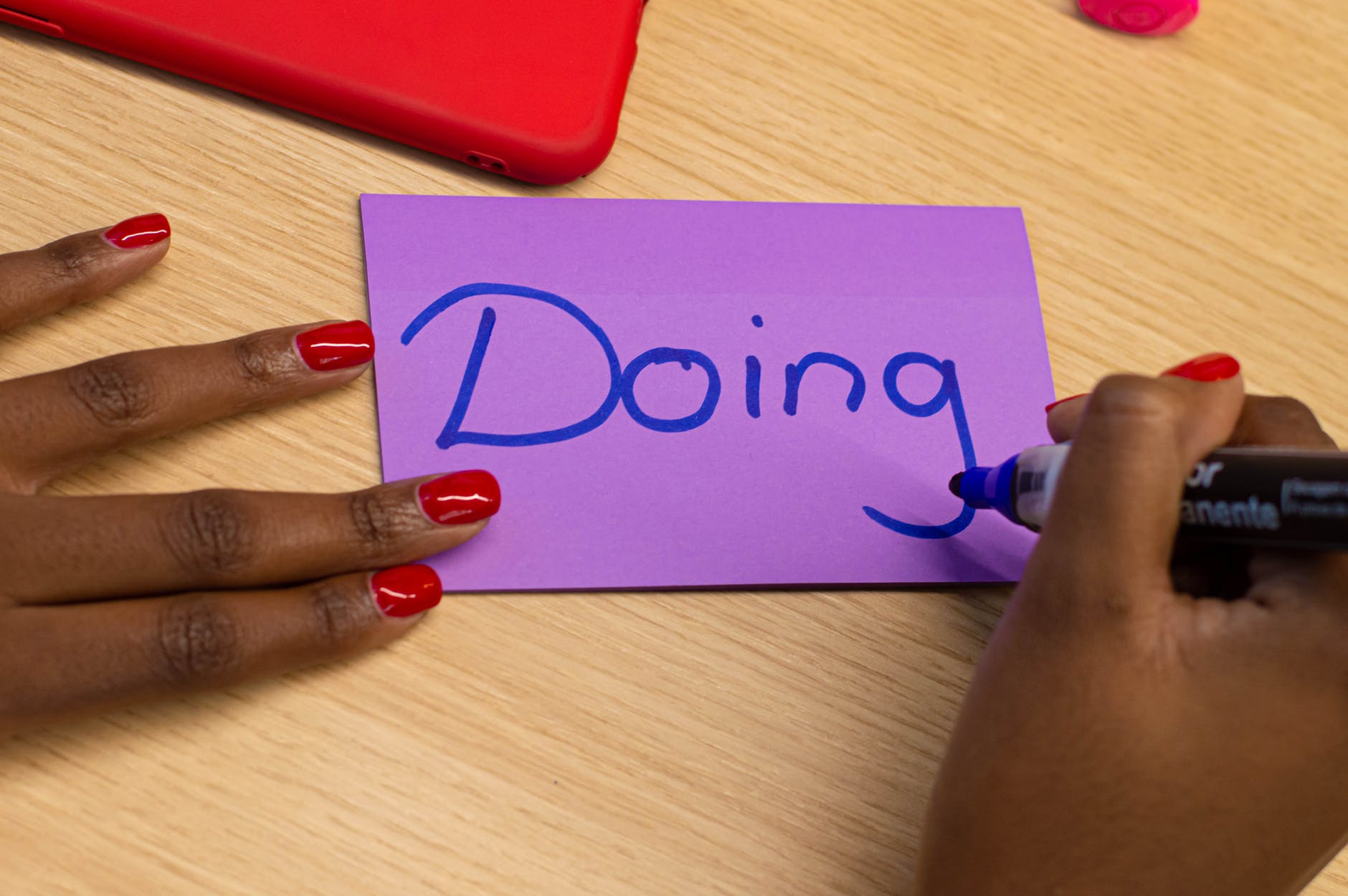 Purple notecard with blue marker and hands. "Doing" is written on the card.