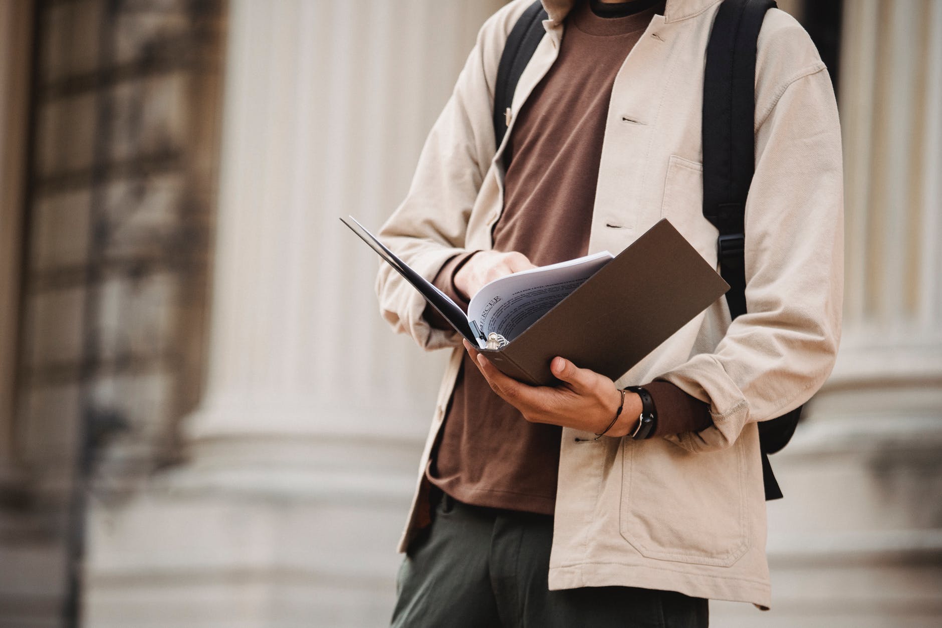 Person holding brown binder. Face is not shown.