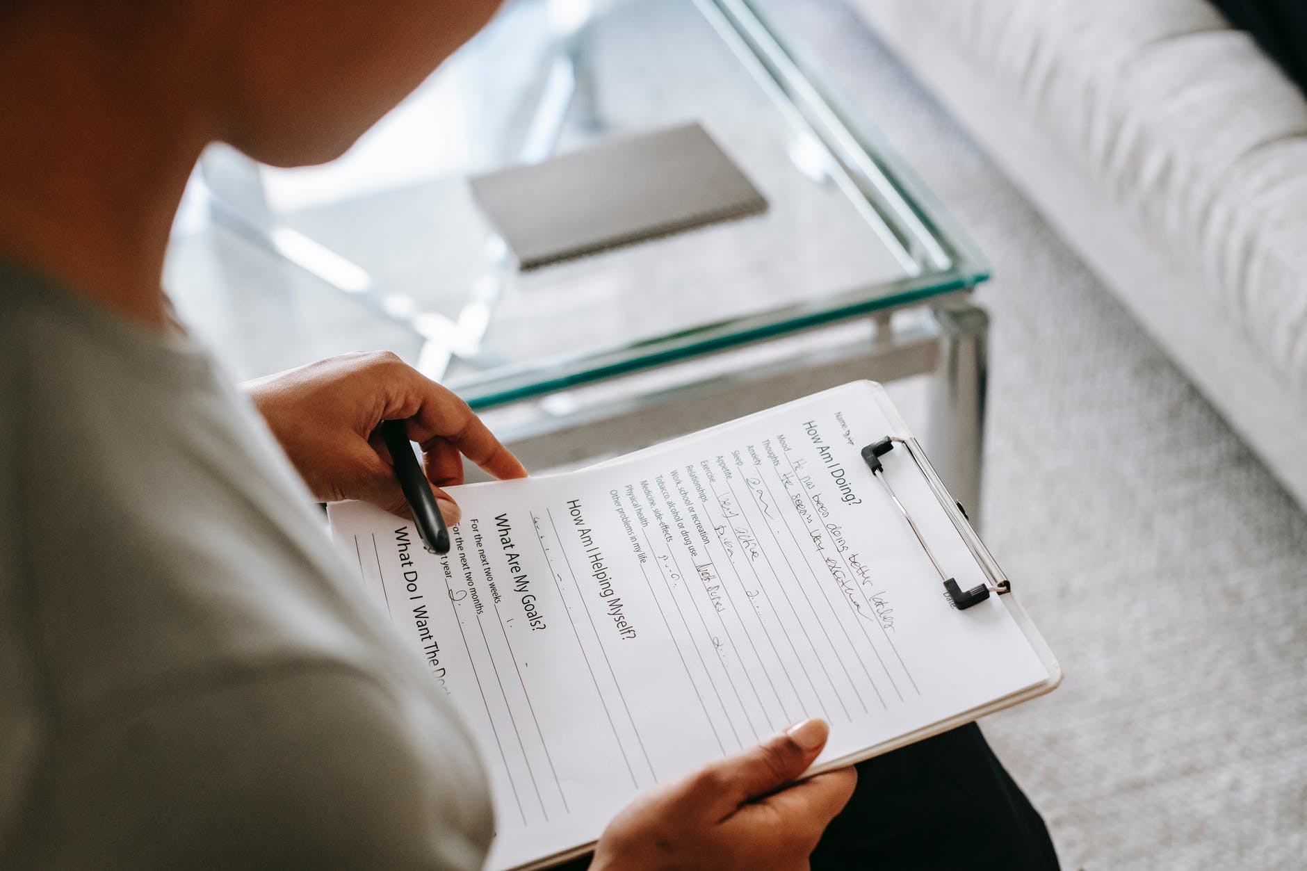 How am I doing and other questions on a sheet of paper on a clipboard being held by two hands.
