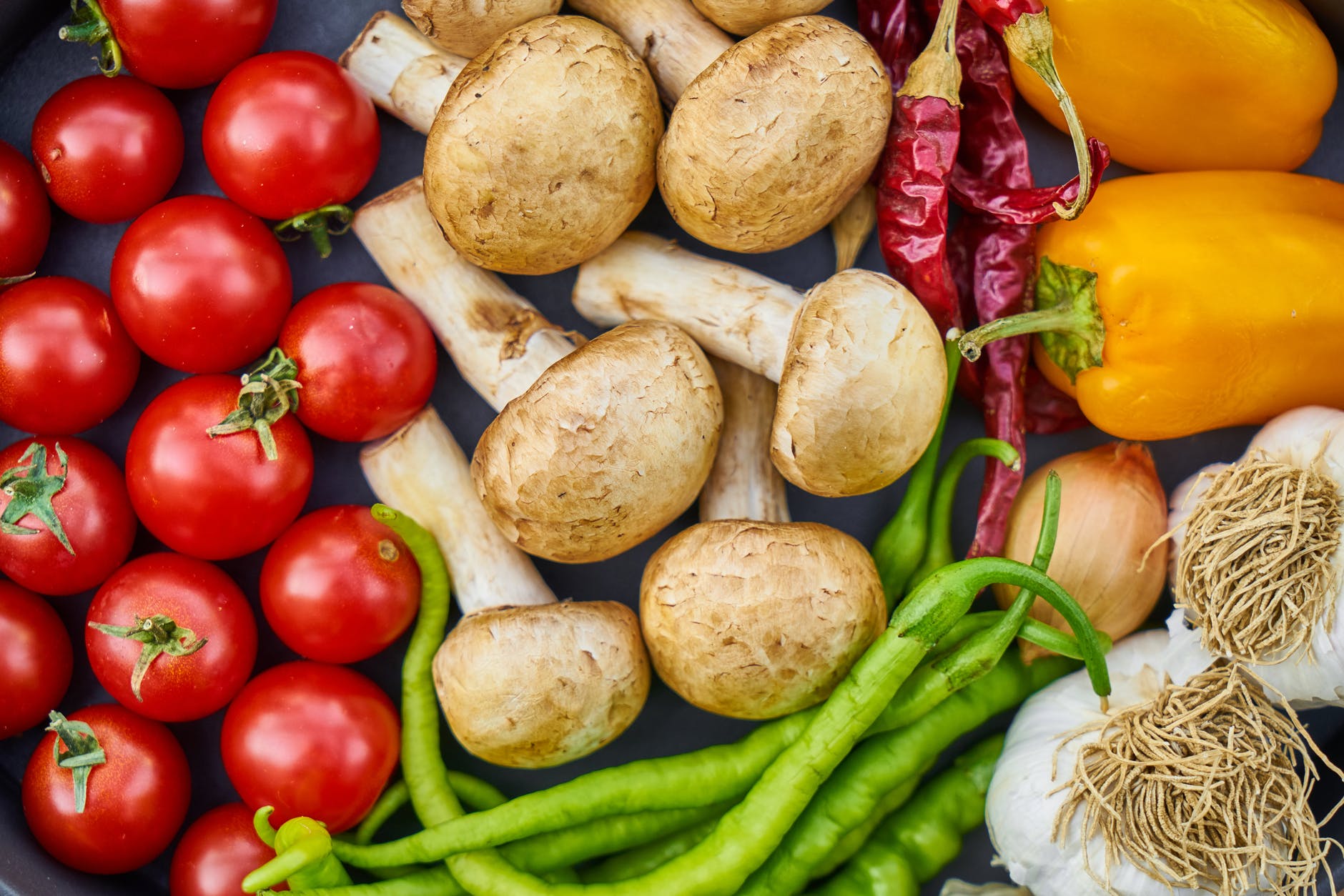 top down view of tomatoes, mushrooms, green beans, and peppers
