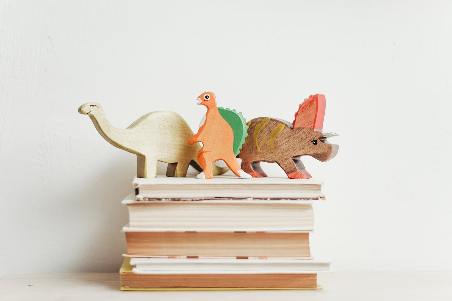 Stack of books with wooden dinosaurs on top