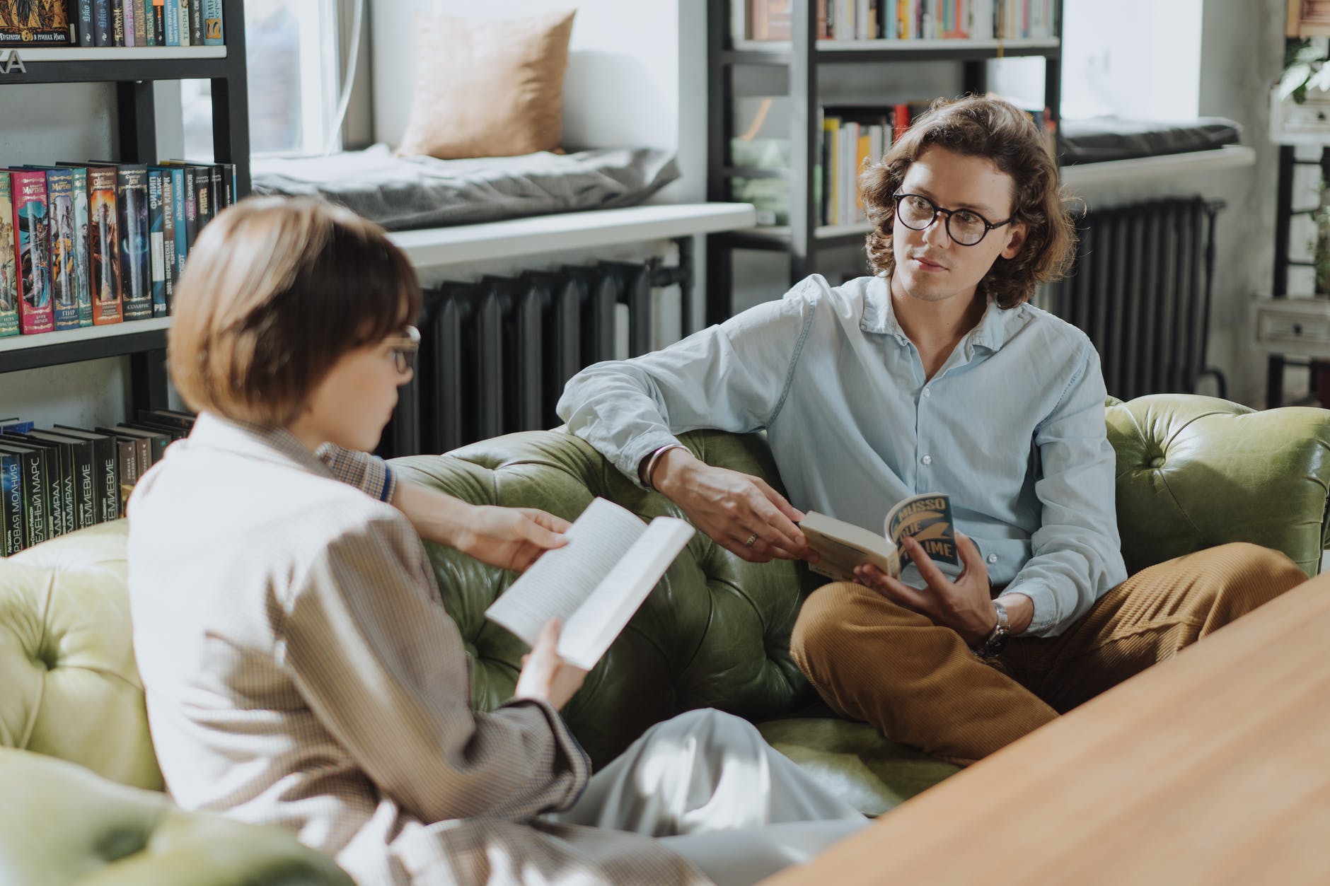 Two people on a couch reading books together.