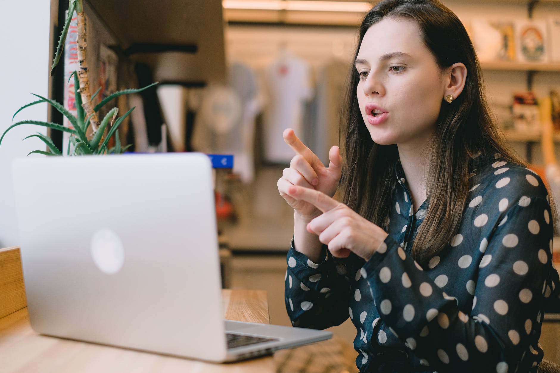 woman with long brown hair signing and pointing to laptop.