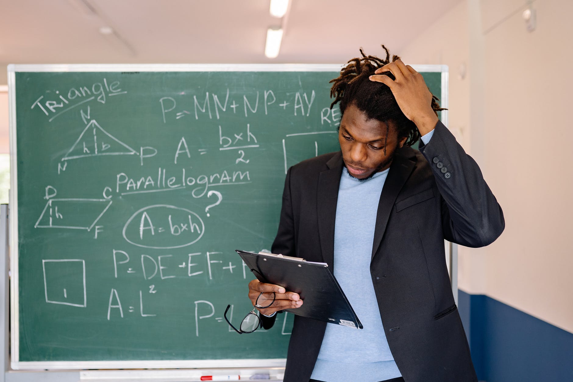 Black man with curly hair in front of chalkboard with geometry